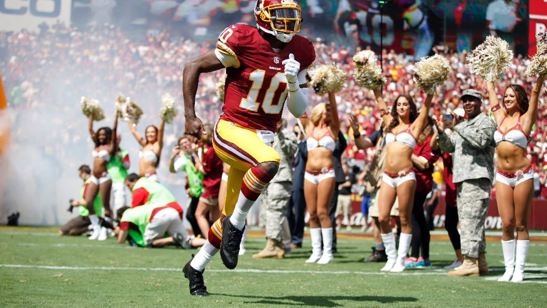 FILE - In this Sept. 14, 2014, file photo, Washington Redskins quarterback Robert Griffin III (10) runs on the field as he is introduced before an NFL football game against the Jacksonville Jaguars in Landover, Md. After six-plus games on the sideline, Robert Griffin III is back as the quarterback of the Washington Redskins for Sunday's, Nov. 2, 2014 game at Minnesota. (AP Photo/Evan Vucci, File)