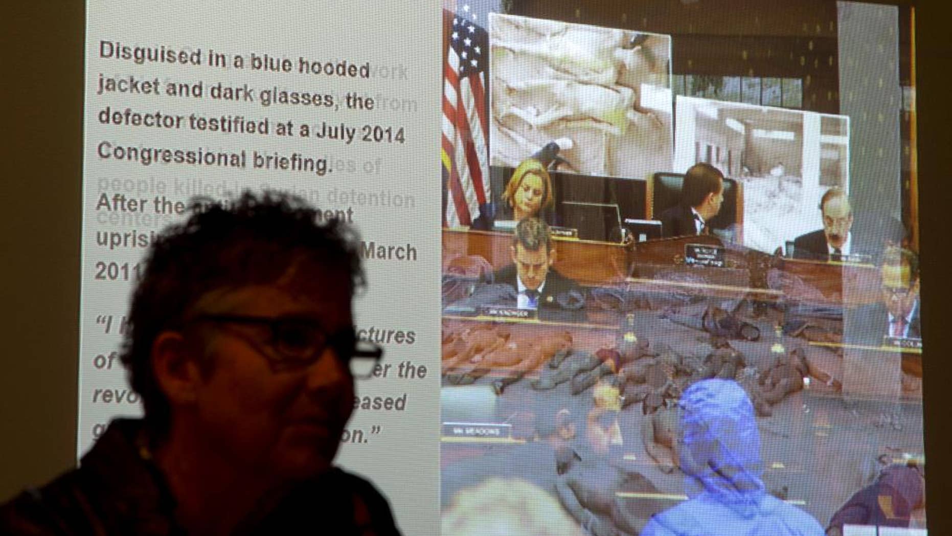 FILE - In this Oct. 15, 2014, file photo, US Holocaust Memorial Museum visitor Marianne Kast, from Fresno, Calif., watches a slide show presentation of images of emaciated and mangled bodies from recent history in Syria in an exhibit entitled "Genocide: The Threat Continues," at the museum in Washington. Almost helpless in the U.N. Security Council to take strong action on Syria, the United States and other states are hoping to shame its government by sponsoring a graphic photo exhibit of detainees who've died in President Bashar Assad's prisons since the country’s conflict began. Fifteen countries will join the opposition Syrian National Coalition on Tuesday, March 10, 2015, at United Nations headquarters to launch the exhibit of portraits showing signs of torture and starvation and to call for an end to the crisis that enters its fifth year this month. (AP Photo/Manuel Balce Ceneta, File)