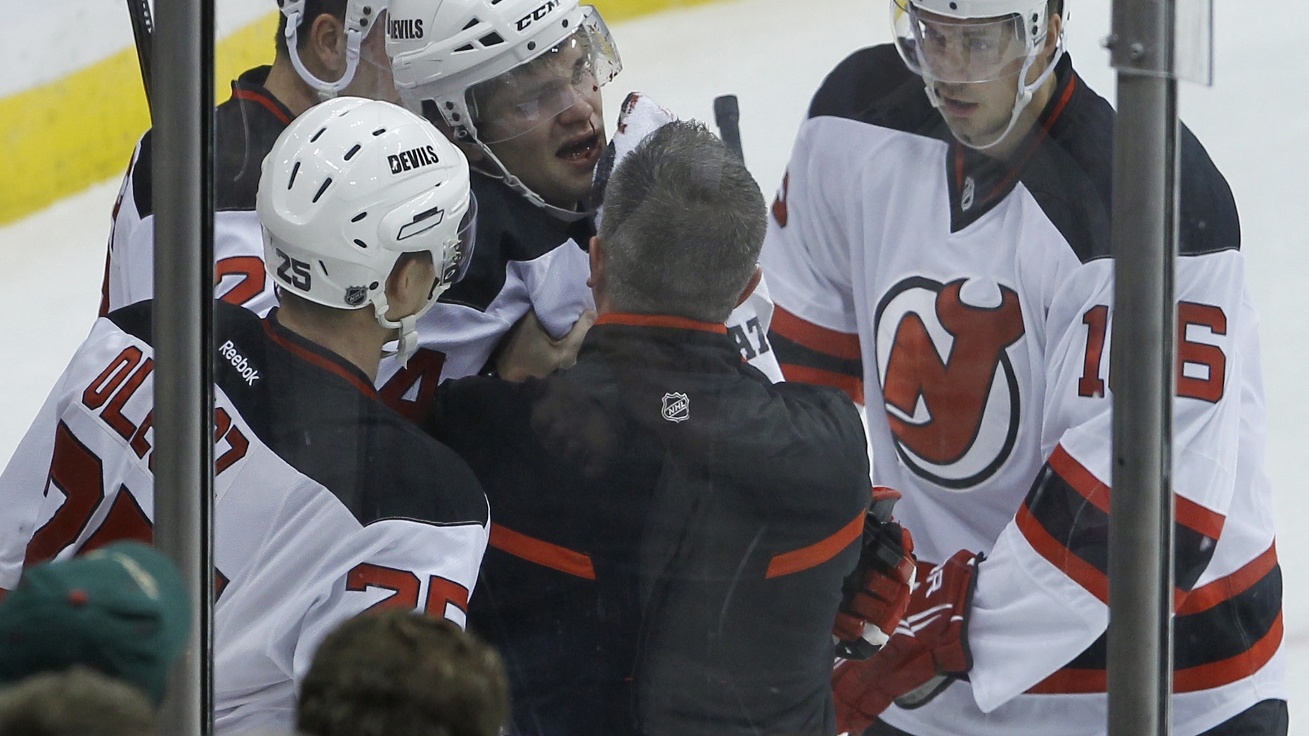 New Jersey Devils defenseman Jon Merrill (34) is helped up from the ice after he was tripped by Minnesota Wild center Torrey Mitchell during the first period of an NHL hockey game in St. Paul, Minn., Sunday, Nov. 3, 2013. Merrill left the game. (AP Photo/Ann Heisenfelt)