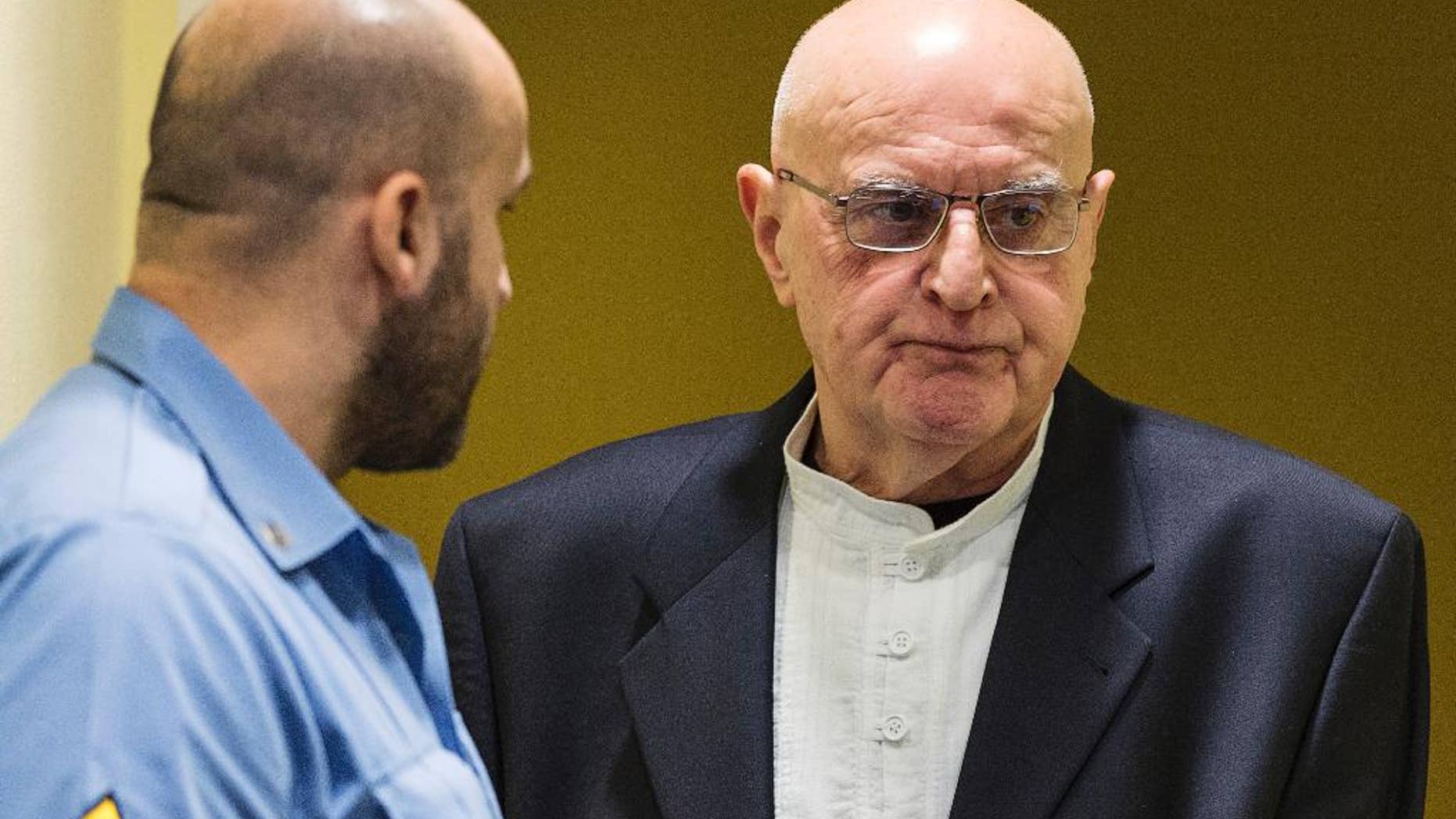 FILE - In this Jan. 30, 2015 file picture Ljubisa Beara, right, enters the courtroom of the International Criminal Tribunal for the former Yugoslavia (ICTY) in The Hague, Netherlands. The Bosnian Serb commander convicted of war crimes over the 1995 Srebrenica massacre has died in a German prison. He was 77. A spokeswoman for Berlin state's justice department told The Associated Press on Friday Feb. 10, 2017 that Ljubisa Beara died Feb. 8. (AP Photo/Michael Kooren, Pool, file )