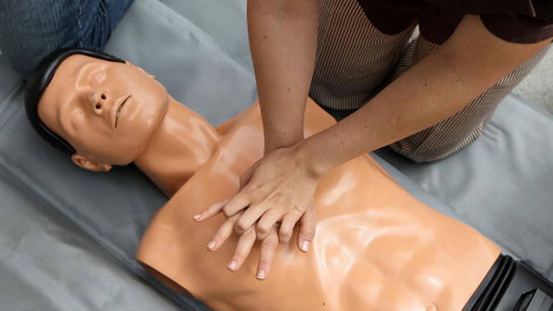 A woman performs chest compressions on a mannequin while learning CPR.