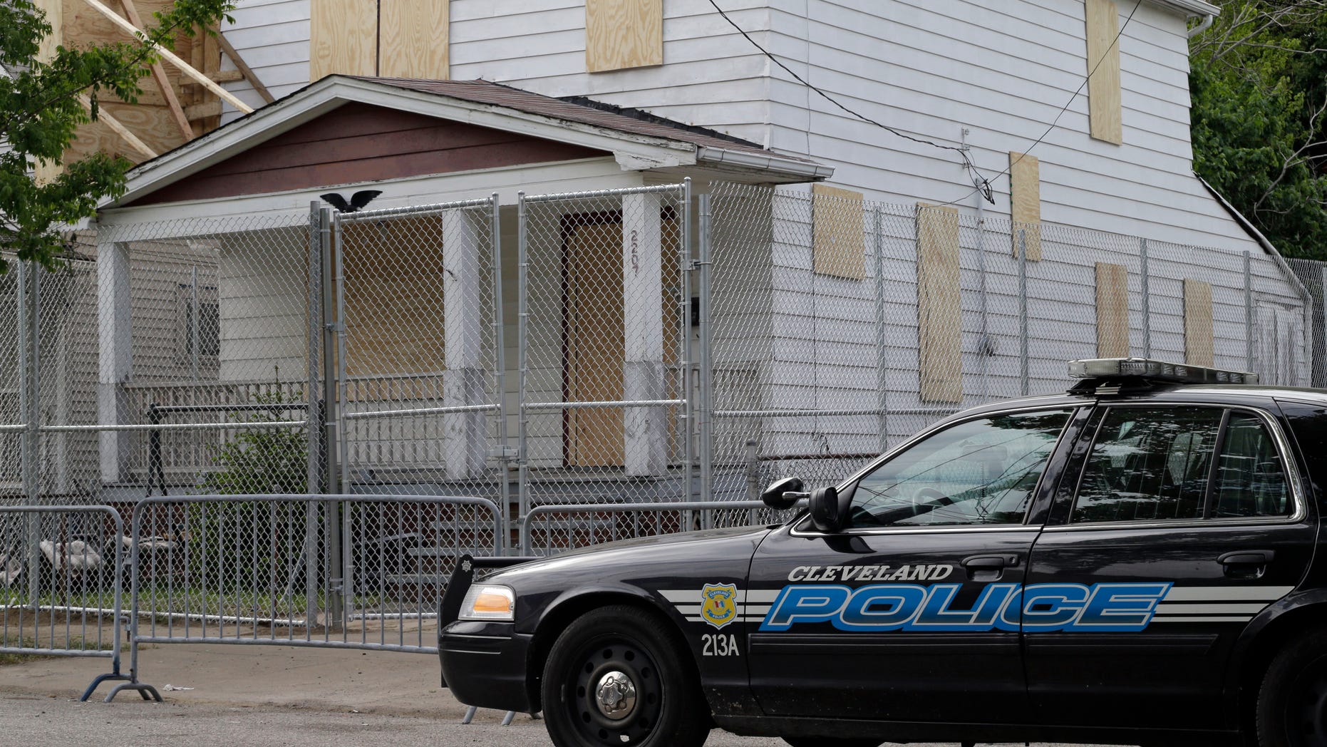 A Cleveland police patrol car sits in front of the boarded up home of Ariel Castro in Cleveland Tuesday, May 14, 2013. Three women were rescued from the house last week after a decade in captivity. Castro is under arrest and charged with rape and kidnapping. (AP Photo/Mark Duncan)