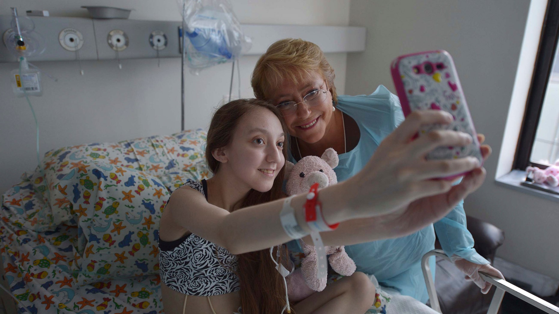 FILE - In this Feb 28, 2015 file photo released by Chile's Presidential Press Office, Valentina Maureira takes a photo of herself with President Michelle Bachelet, at the Catholic University hospital in Santiago, Chile. The girl, ailing from cystic fibrosis, who made a public plea for permission to end her life has died. Her father, Fredy Maureira, confirmed that Valentina passed away on Thursday, May 13, 2015, to local Radio Bio Bio, saying the 14-year-old is finally resting in peace. (AP Photo/Chile Presidential Press Office, Ximena Navarro, File)
