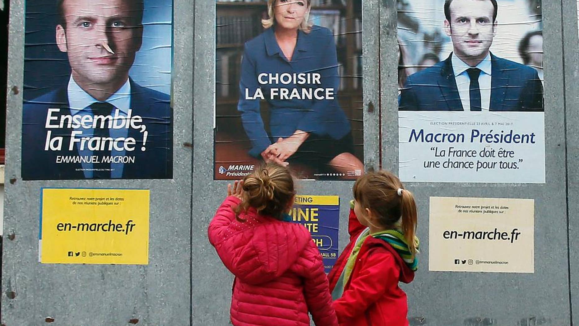 Children walk past election campaign posters for French centrist presidential candidate Emmanuel Macron and far-right candidate Marine Le Pen, in Osses, southwestern France, Friday May 5, 2017. France will vote on Sunday May 7 in the second round of the presidential election. (AP Photo/Bob Edme)