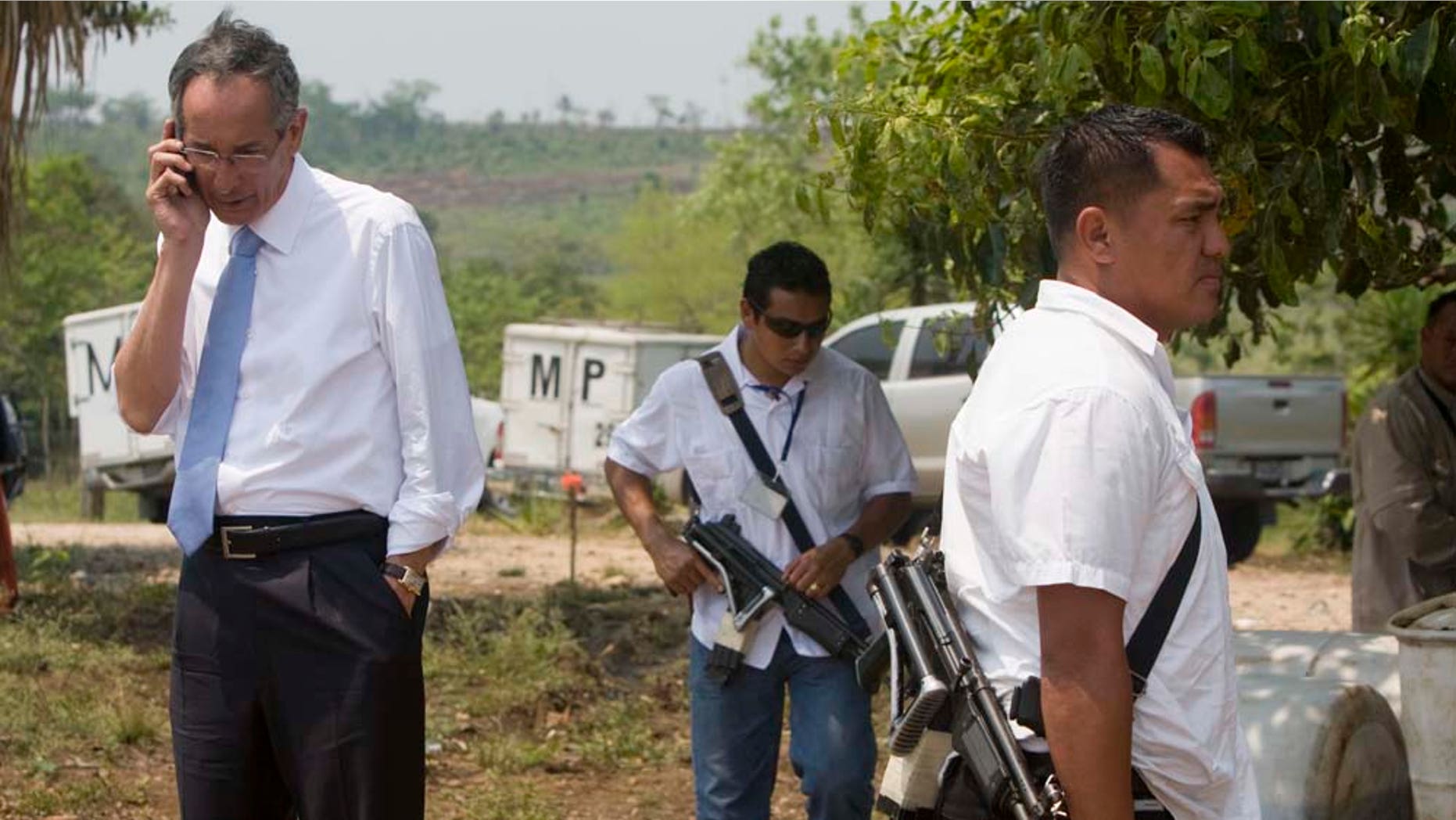 Guatemala's President Alvaro Colom, left, talks on a mobile phone while inspecting the site of a massacre at a local ranch in the hamlet Caserio La Bomba, in La Libertad, northern Guatemala, Monday, May 16, 2011. Assailants killed Sunday at least 29 people, including two children and two women, decapitating most of the victims on the ranch near the Mexico border, according to National Civil Police spokesman Donald Gonzalez. (AP Photo/Moises Castillo)