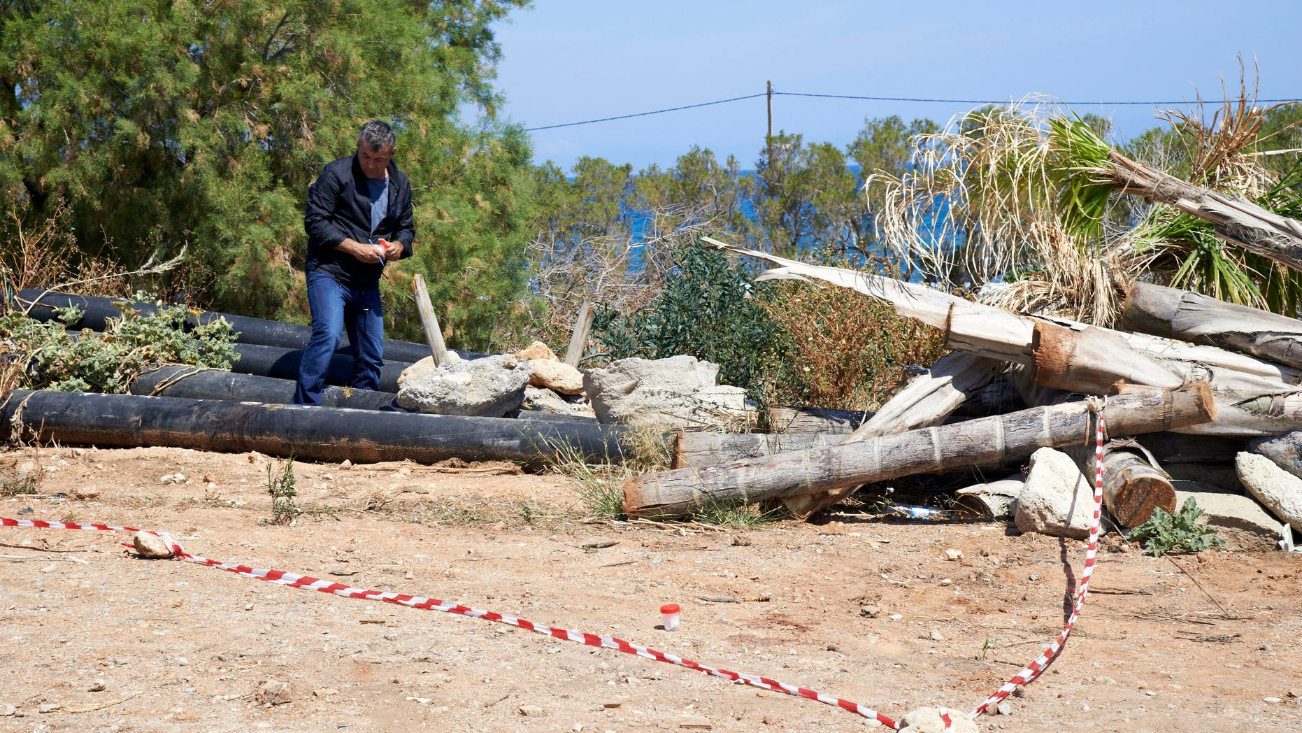 A plain clothed police officer investigates an area where a 12-year-old Russian boy was found wounded in the holiday resort of Hersonissos, on the Greek island of Crete on Wednesday, May 15, 2013. Greek authorities say the boy vacationing on the island of Crete has been found stabbed multiple times and is being airlifted to Athens for treatment of serious injuries. Police have detained a 20-year-old Dutch man who was employed at the child's hotel. (AP Photo/Bastian Parschau)