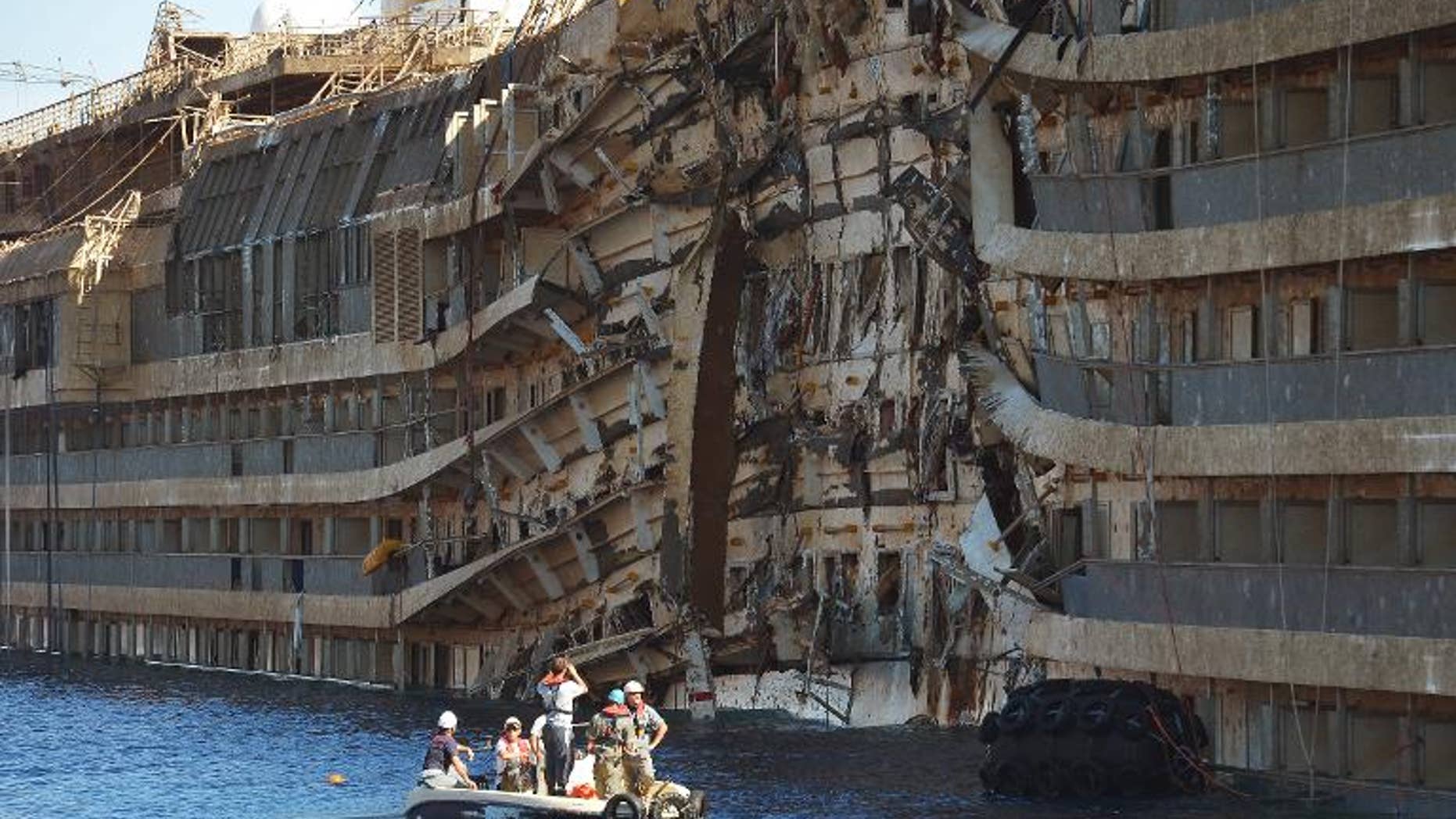 Workers from US salvage company Titan and Italian firm Micoperi inspect the wreck of the Costa Concordia cruise ship after it was hauled out of the water, in Giglio harbour on September 18, 2013