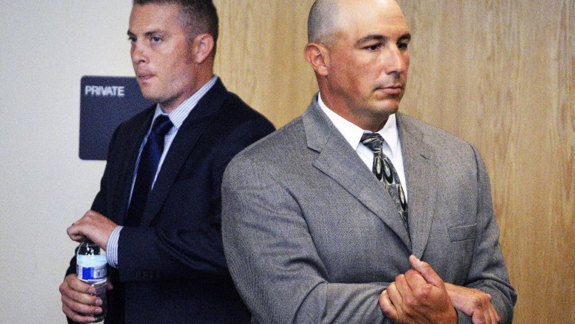 Former Albuquerque Detective Keith Sandy, center, listens to a special prosecutor tell a judge at a preliminary hearing that he unlawfully shot a homeless camper who posed no threat in Albuquerque, N.M. on Monday, Aug. 3, 2015. Sandy and Albuquerque officer Dominique Perez are facing second-degree murder charges in the 2014 fatal shooting death of 38-year-old James Boyd. (AP Photo/Russell Contreras)