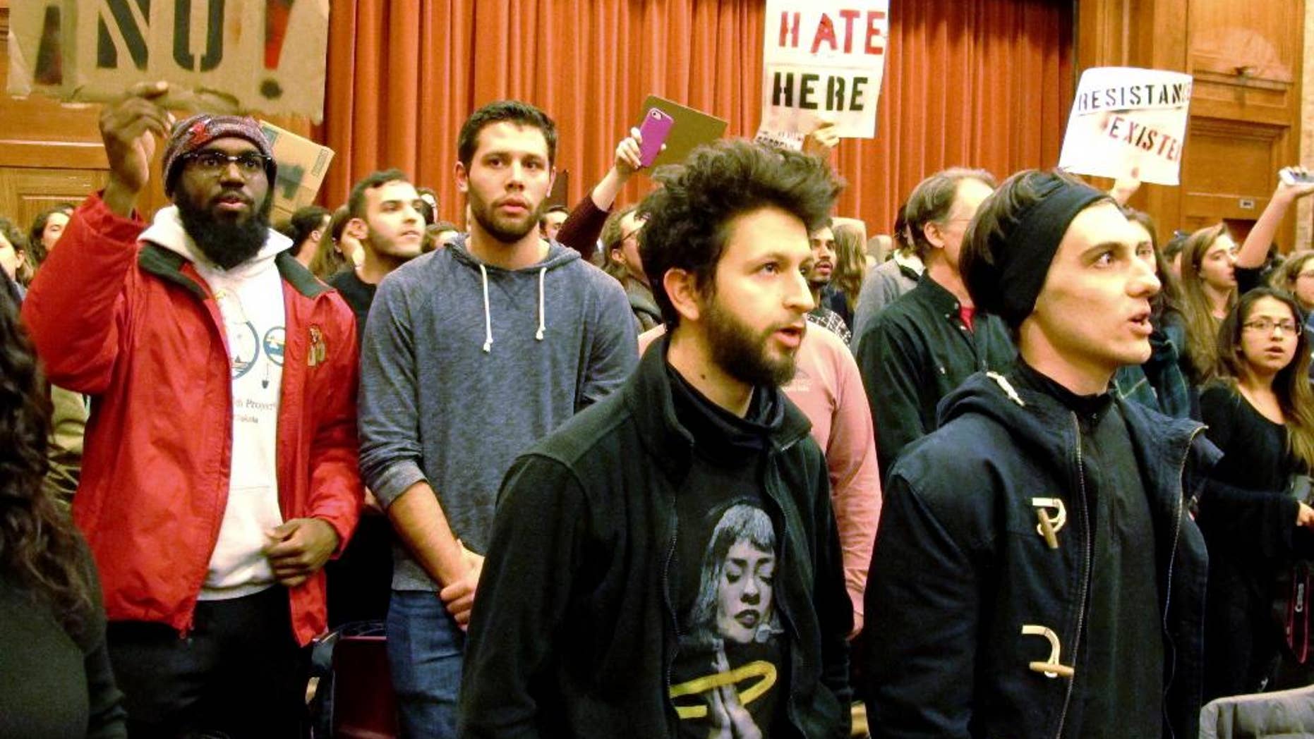 File-This March 2, 2017, file photo shows Middlebury College students turning their backs to Charles Murray, unseen, during his lecture in Middlebury, Vt. Up to 70 students face disciplinary measures over the protest of author Charles Murray, who spoke at Middlebury College in March. A professor was injured in a melee afterward. (AP Photo/Lisa Rathke, File)