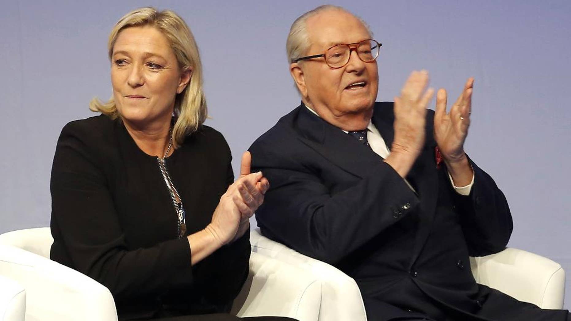 FILE - In this Saturday Nov. 29, 2014 file photo, French far-right Front National leader Marine Le Pen and her father Jean-Marie Le Pen applaud in Lyon, central France. A French court has reinstated Thursday July 2, 2015 Jean-Marie Le Pen as a member of the far right National Front party he founded decades ago, sending a biting blow to his daughter and party president Marine Le Pen, who had suspended him after a series of controversial and anti-Semitic statements. (AP Photo/Laurent Cipriani, File)