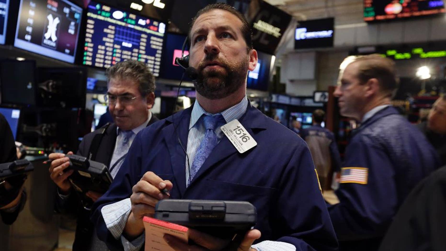 Greg Mulligan, center, works with fellow traders on the floor of the New York Stock Exchange Tuesday, Aug. 19, 2014. Better news on home building and corporate earnings are sending stocks higher. (AP Photo/Richard Drew)