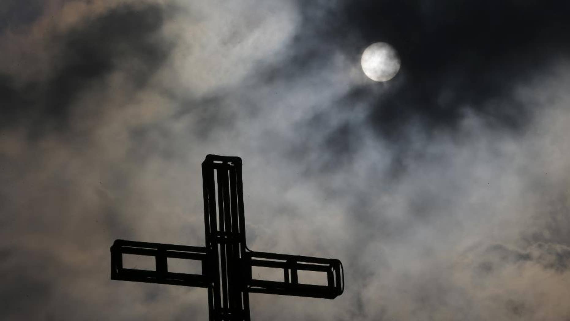 Dark clouds partially cover the sun above a church on Easter Sunday April 5, 2015 in suburban Quezon city, north of Manila, Philippines. Tropical storm Maysak weakened before hitting the Philippines' northeastern coast Sunday, driving away thousands of Lenten holiday vacationers and tourists. (AP Photo/Aaron Favila)