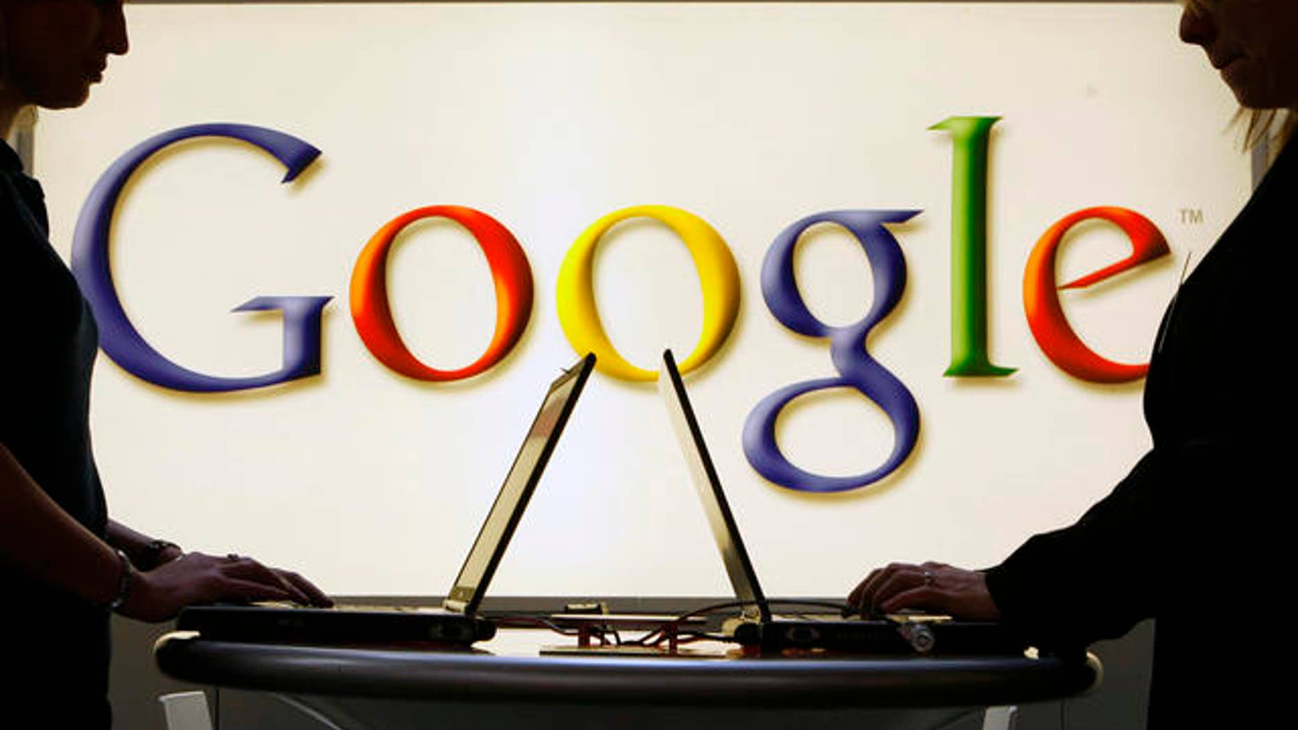 FILE: Exhibitors of the Google company work on laptop computers in front of an illuminated sign of the Google logo at the industrial fair Hannover Messe in Hanover, Germany.
