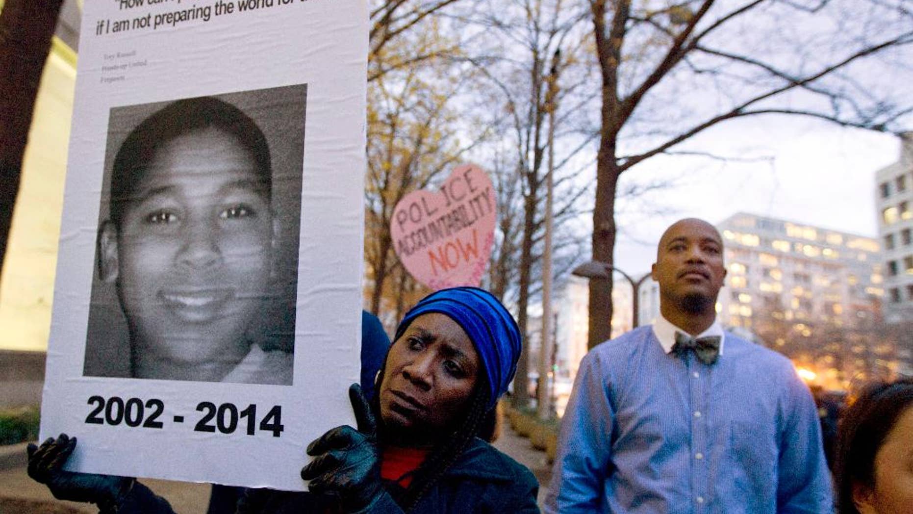 FILE - In this Dec. 1, 2014 file photo, Tomiko Shine holds up a picture of Tamir Rice during a protest in Washington. A 911 dispatcher who took a call that led to a white police officer's fatal shooting of Rice, a 12-year-old black boy who'd been playing with a pellet gun outside a Cleveland recreation center, has been suspended for eight days. Police Chief Calvin Williams stated in a disciplinary letter Constance Hollinger violated protocol. (AP Photo/Jose Luis Magana, File)