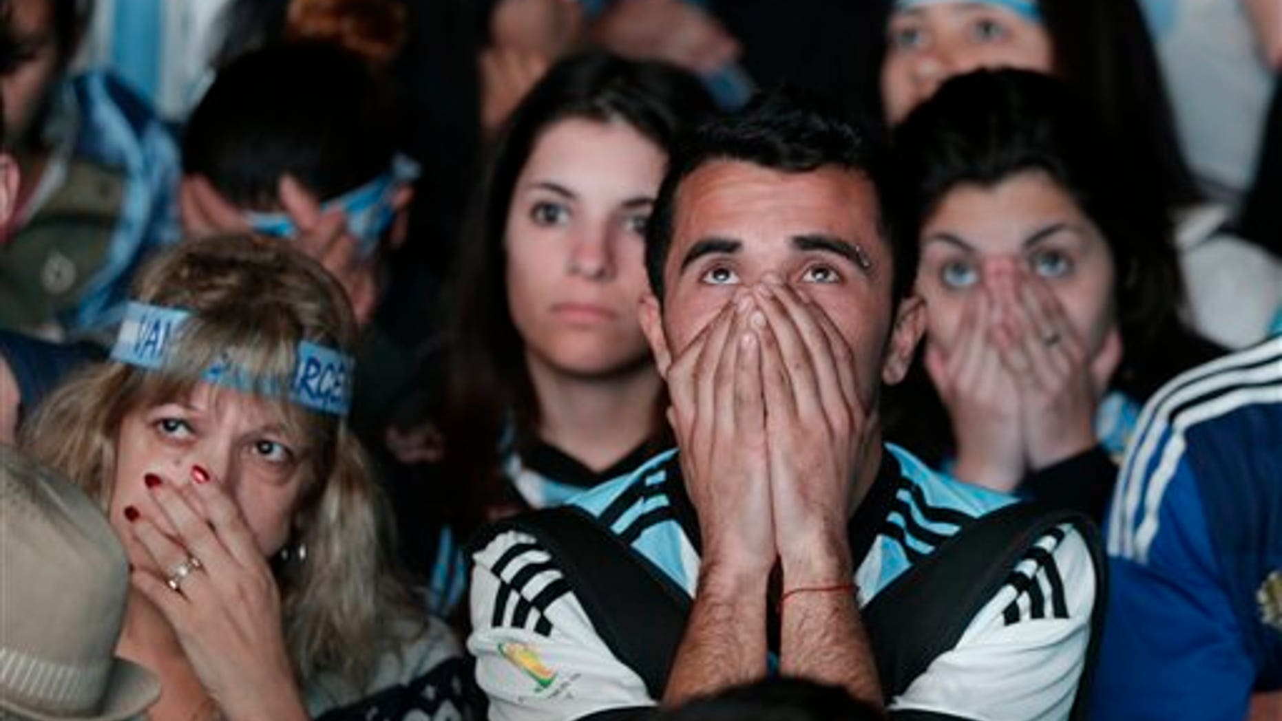 Argentina soccer fans watch in disbelief the final World Cup match between Argentina and Germany on an outdoor television screen set up in Buenos Aires, Argentina, Sunday, July 13, 2014. Mario Goetze volleyed in the winning goal in extra time to give Germany its fourth World Cup title with a 1-0 victory over Argentina. (AP Photo/Jorge Saenz)