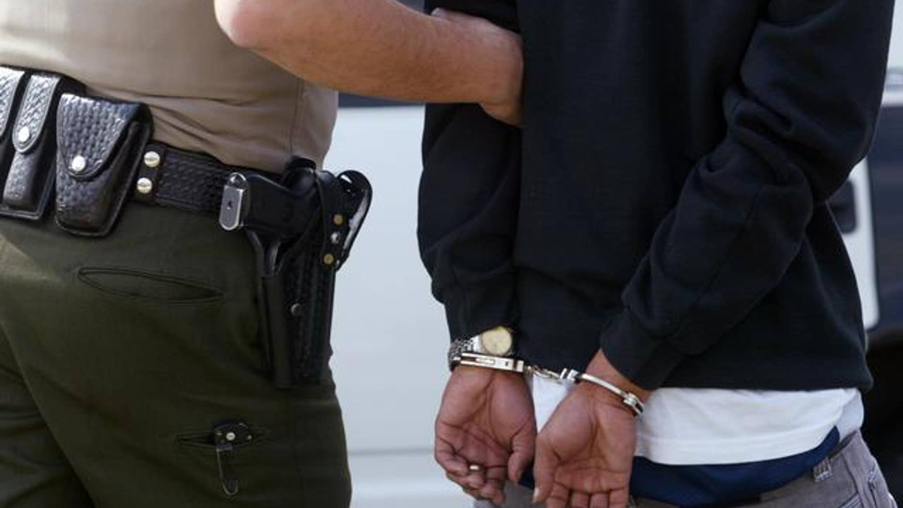 ** ADVANCE FOR TUESDAY FEB. 25 ** A Los Angeles County Sheriff's Department deputy leads a suspect to a patrol car after the suspect's arrest following a carjacking Wednesday, Feb.19, 2003, in Lynwood, Calif. The sheriff's department is considering eliminating its nationally-recognized anti-gang Operation Safe Streets unit in response to state funding reductions to the county due to the state's budget deficit. (AP Photo/Damian Dovarganes)