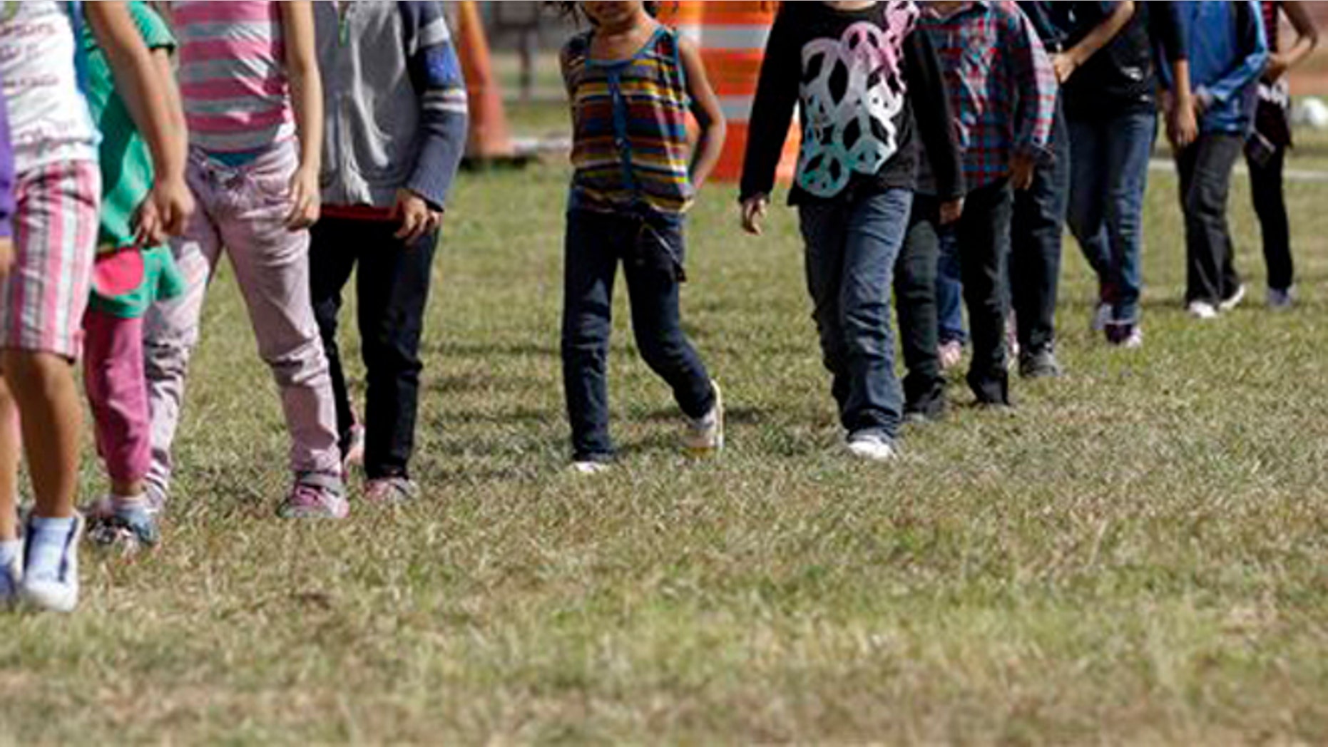 Detainees walk in a line at a U.S. Customs and Border Protection processing facility, June 18, 2014, in Brownsville,Texas.