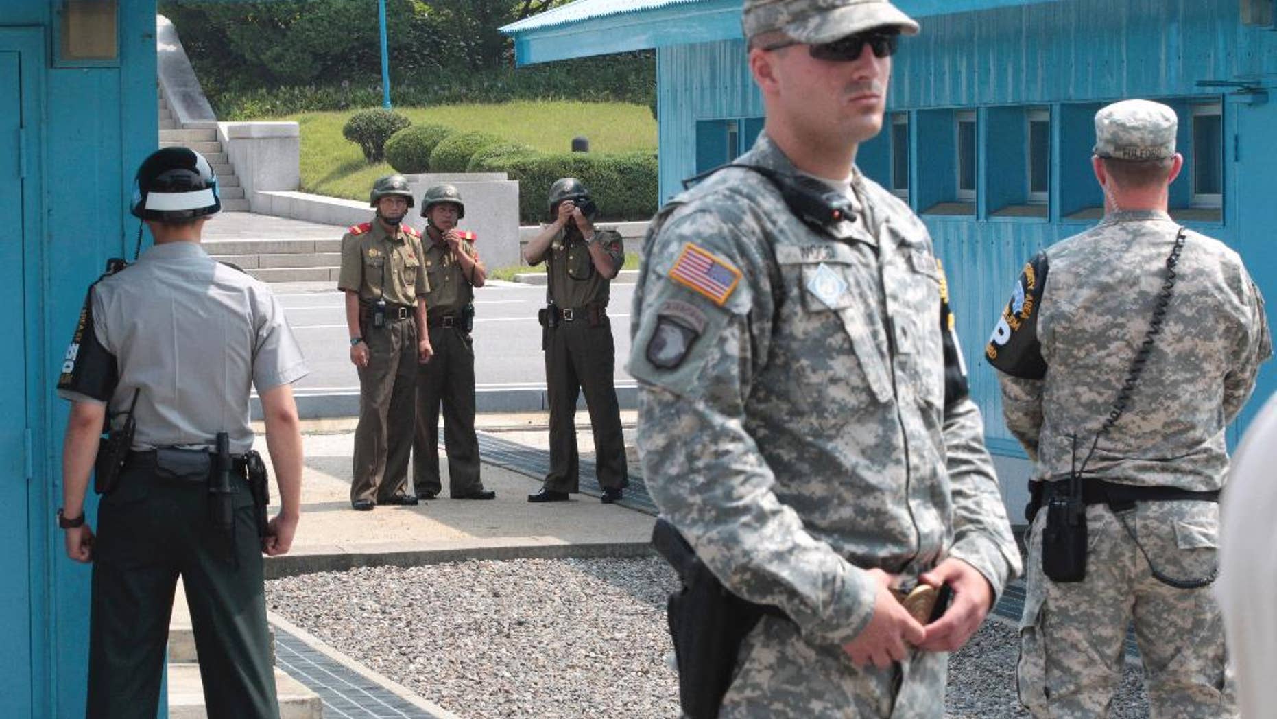 FILE - In this July 27, 2014 file photo, North Korean army soldiers watch the south side while a South Korean and United States Army soldiers stand guard at the border villages of Panmunjom in Paju, South Korea. North Korea has threatened on Saturday, Aug. 27, 2016, to aim fire at the lighting equipment used by American and South Korean troops at a truce village inside the Demilitarized Zone that divides the two Korea. (AP Photo/Ahn Young-joon, File)
