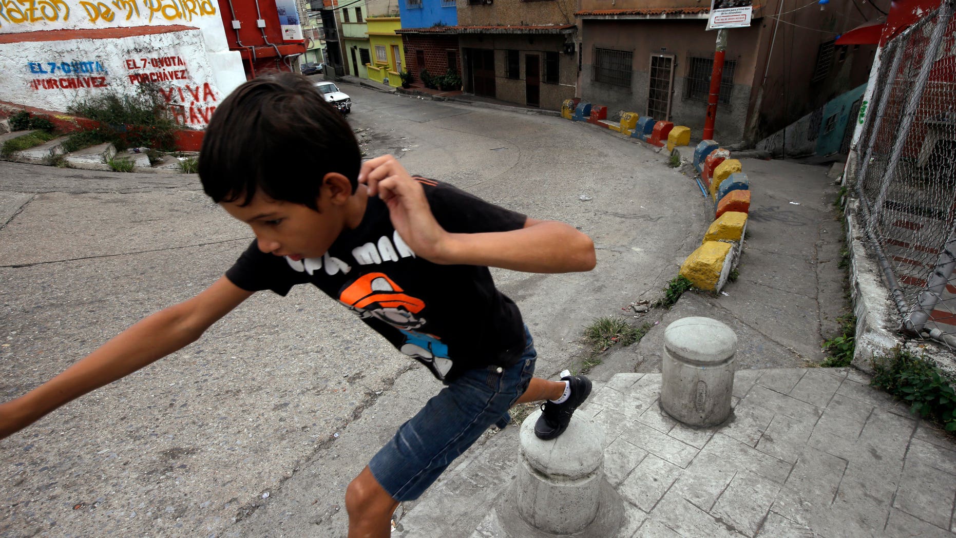 A boy plays in front of a graffiti that reads in Spanish "Chavez, heart of my homeland" at the neighborhood of Petare in Caracas, Venezuela, Monday, Dec. 17, 2012. Smarting after a bruising loss in state elections, Venezuela's opposition will now be forced to reassess its strategy and rebuild quickly to prepare for presidential elections that many expect could be called to replace ailing leftist President Hugo Chavez. (AP Photo/Fernando Llano)