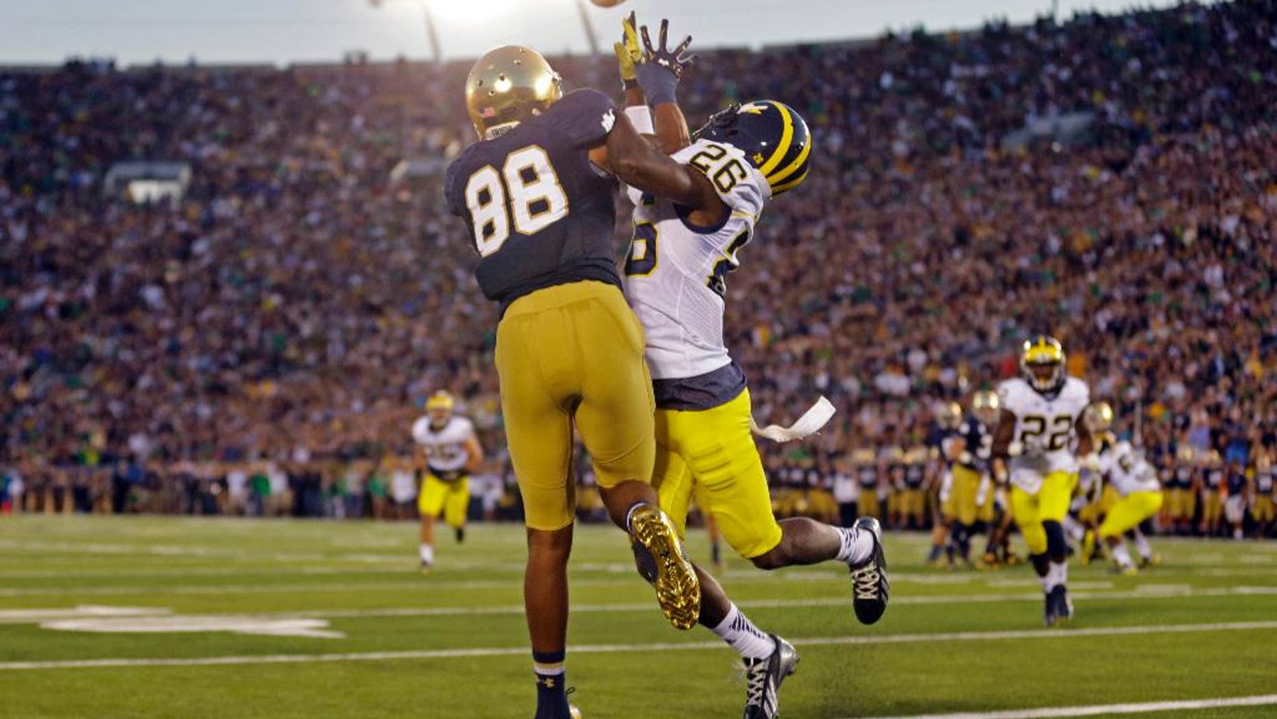 Michigan defensive back Jourdan Lewis, right, interferes with Notre Dame wide receiver Corey Robinson in as he attempts a catch in the end zone during the first half of an NCAA college football game in South Bend, Ind., Saturday, Sept. 6, 2014. (AP Photo/Michael Conroy)