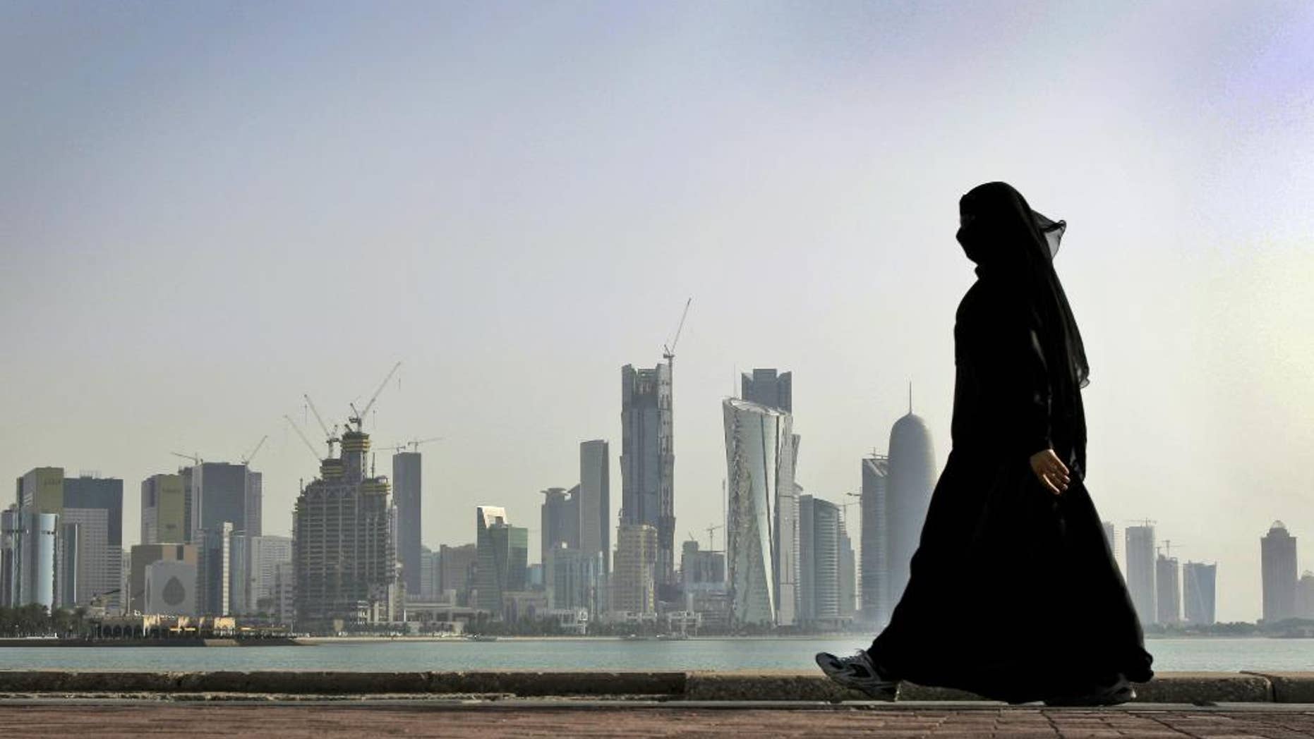 In this May 14, 2010 file photo, a Qatari woman walks in front of the city skyline in Doha, Qatar.