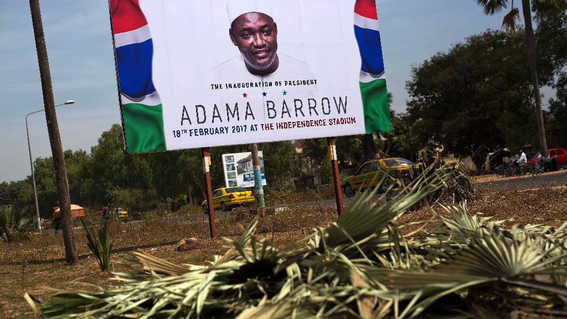 A billboard calling for the inauguration of Adam Barrow as president in Feb. 18 is set on the side of a road in Serrukunda, Gambia, Friday Jan. 27, 2017. Hundreds of thousands turned out Thursday to greet President Adama Barrow, a week after he took the oath of office in neighboring Senegal. (AP Photo/Jerome Delay)