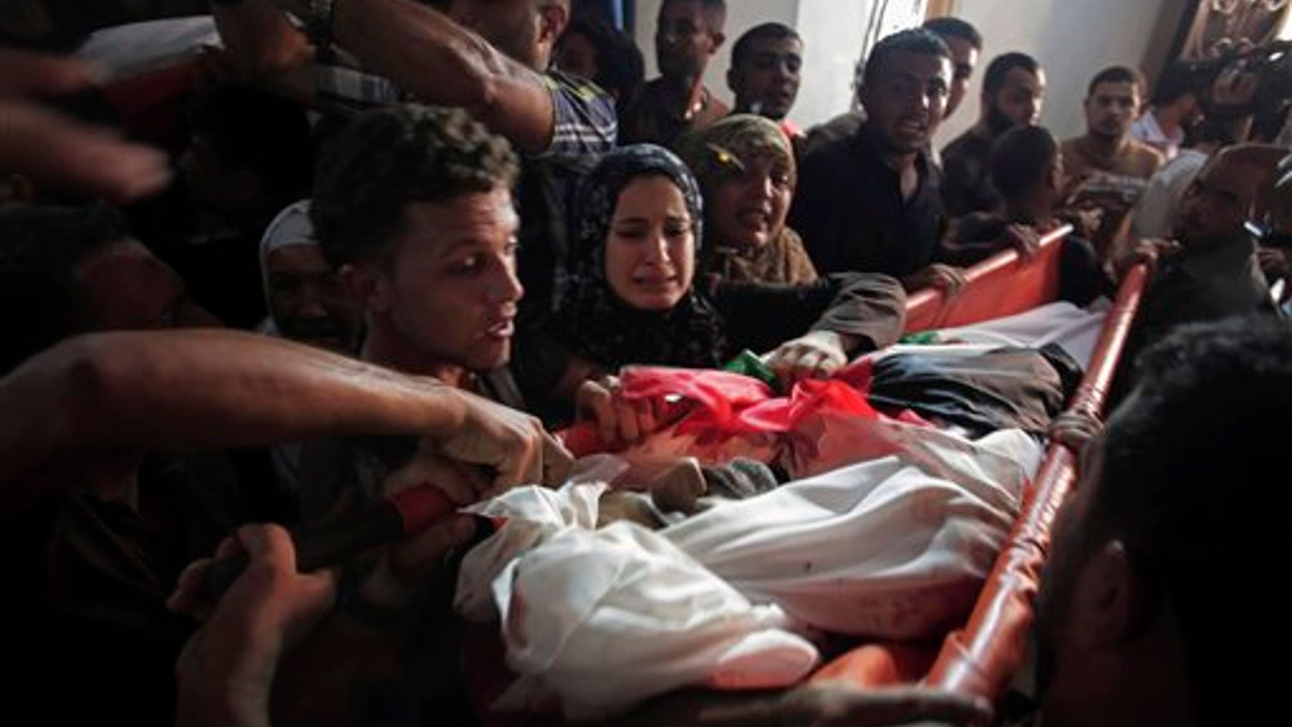 Palestinian relatives mourn over the body of one of the five members of the Hamad family who were killed in an Israeli missile strike late Tuesday in the family house during their funeral in town of Beit Hanoun, northern Gaza Strip, Wednesday, July 9, 2014. The Israeli army on Wednesday intensified its offensive on the Hamas-run Gaza Strip, striking Hamas sites and killing more than a dozen of people on the second day of a military operation it says is aimed at quenching rocket fire against Israel.