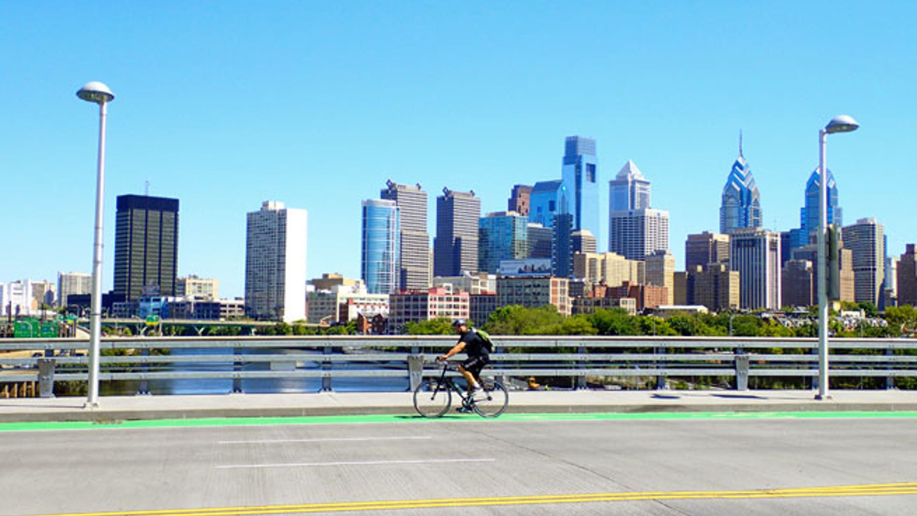 Philadelphia, PA, USA â August 28, 2014: Bicyclist on the South Street Bridge with the Philadelphia Skyline behind him.