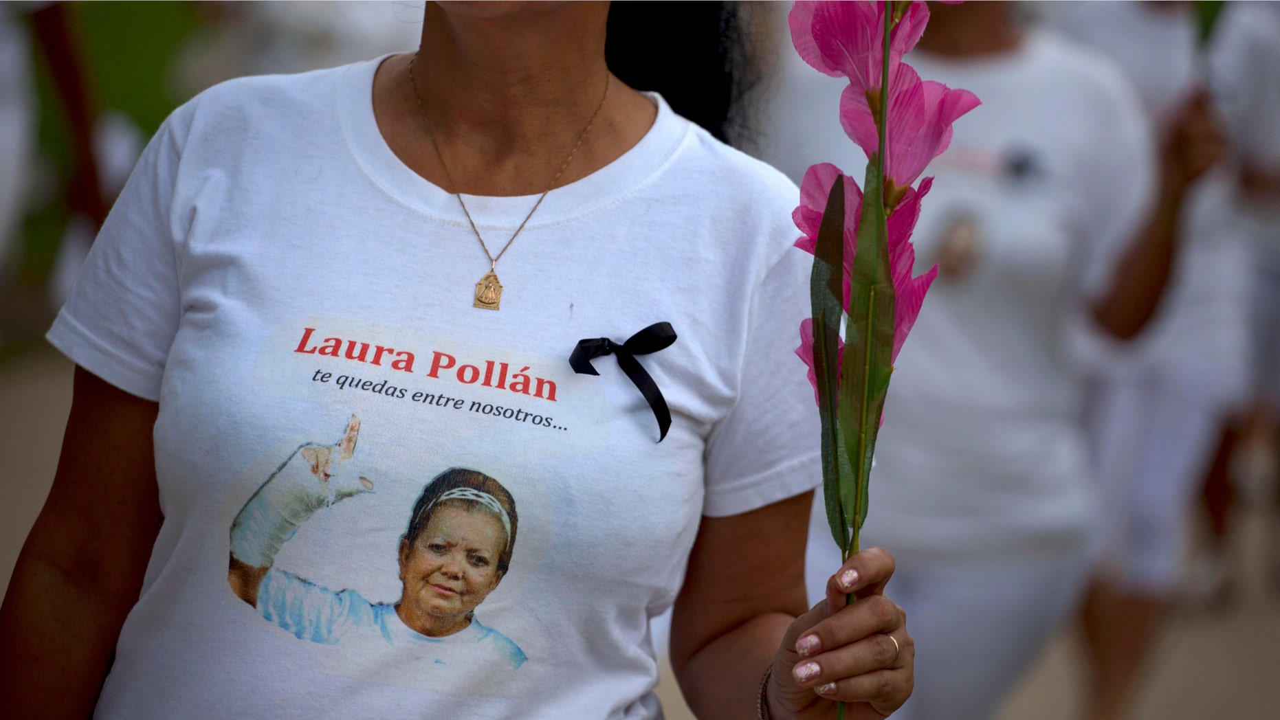 A member of Cuba's Ladies in White dissident group, wearing a T-shirt with an image of the late co-founder of the group, Laura Pollan, participates in a march in Havana, Cuba, Sunday, Oct 14, 2012. The T-shirt reads in Spanish "you stay with us." (AP Photo/Ramon Espinosa)