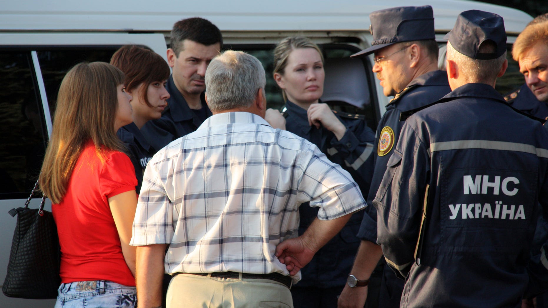 Rescue workers speak with people near the Suhodilska-Eastern mine, where a blast killed at least 16 workers and injured three others, in Suhodilska, Luhansk region, Ukraine, Friday, July 29, 2011. Rescuers were looking for nine miners missing after a powerful pre-dawn blast at the Suhodilska-Eastern mine in the Luhansk region that killed 16 workers and injured three others.