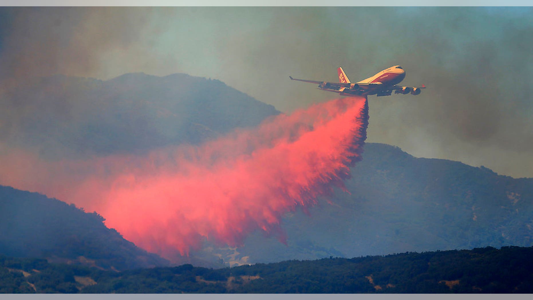 A 747 Global air tanker makes a drop on a wildfire in Scotts Valley, Friday, Aug. 3, 2018, near Lakeport, Calif. (Kent Porter /The Press Democrat via AP)