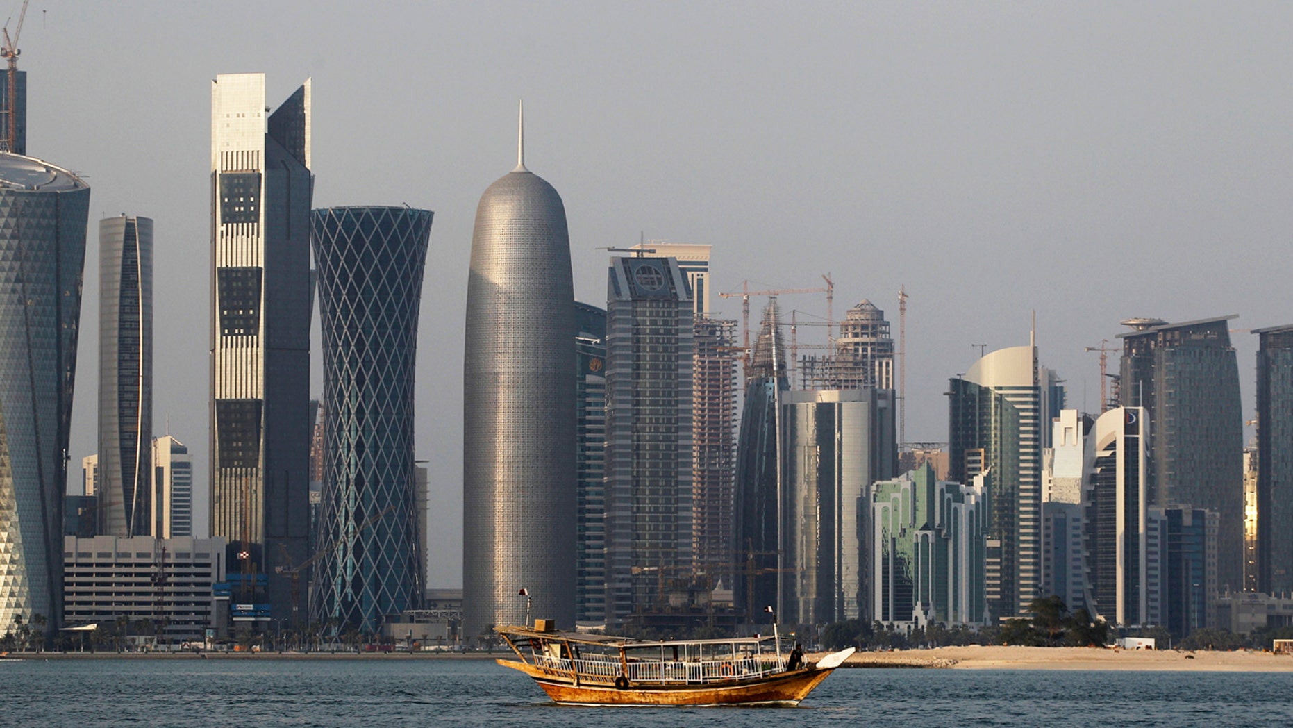 In this Thursday Jan. 6, 2011 file photo, a traditional dhow floats in the Corniche Bay of Doha, Qatar, with tall buildings of the financial district in the background.