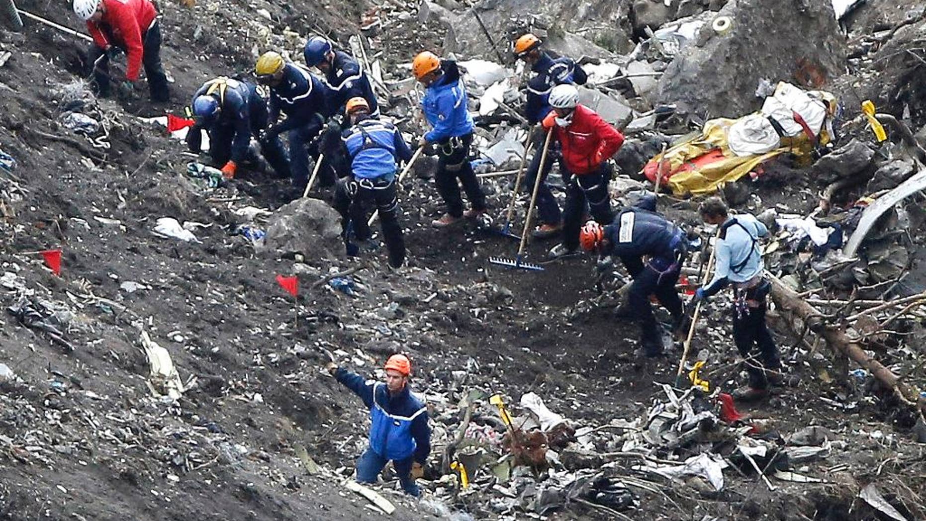 FILE - In this Thursday March 26, 2015 file photo, rescue workers inspect the debris from the Germanwings jet at the crash site near Seyne-les-Alpes, France. The somber mission to recover the remains of 150 people killed instantly when the Germanwings flight crashed full speed into the Col de Mariaud is not a quiet one and crucial physical evidence for the crash investigation can be gathered only when the mountains cooperate. (AP Photo/Laurent Cipriani, File)