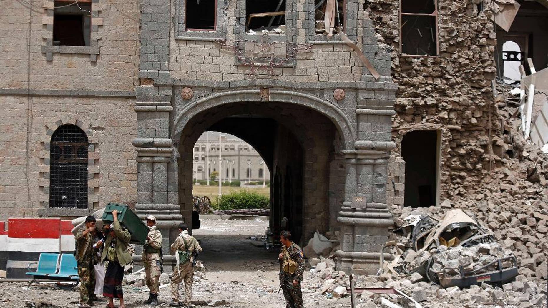 Shiite rebels known as Houthis wearing army uniforms stand guard in front of Yemen's Defense Ministry building after it was damaged by Saudi-led airstrikes in Sanaa, Yemen, Wednesday, June 10, 2015. A series of airstrikes by the Saudi-led military coalition on Tuesday struck the building, which is under the control of Shiite rebels who last year seized the capital, Sanaa, officials said. (AP Photo/Hani Mohammed)