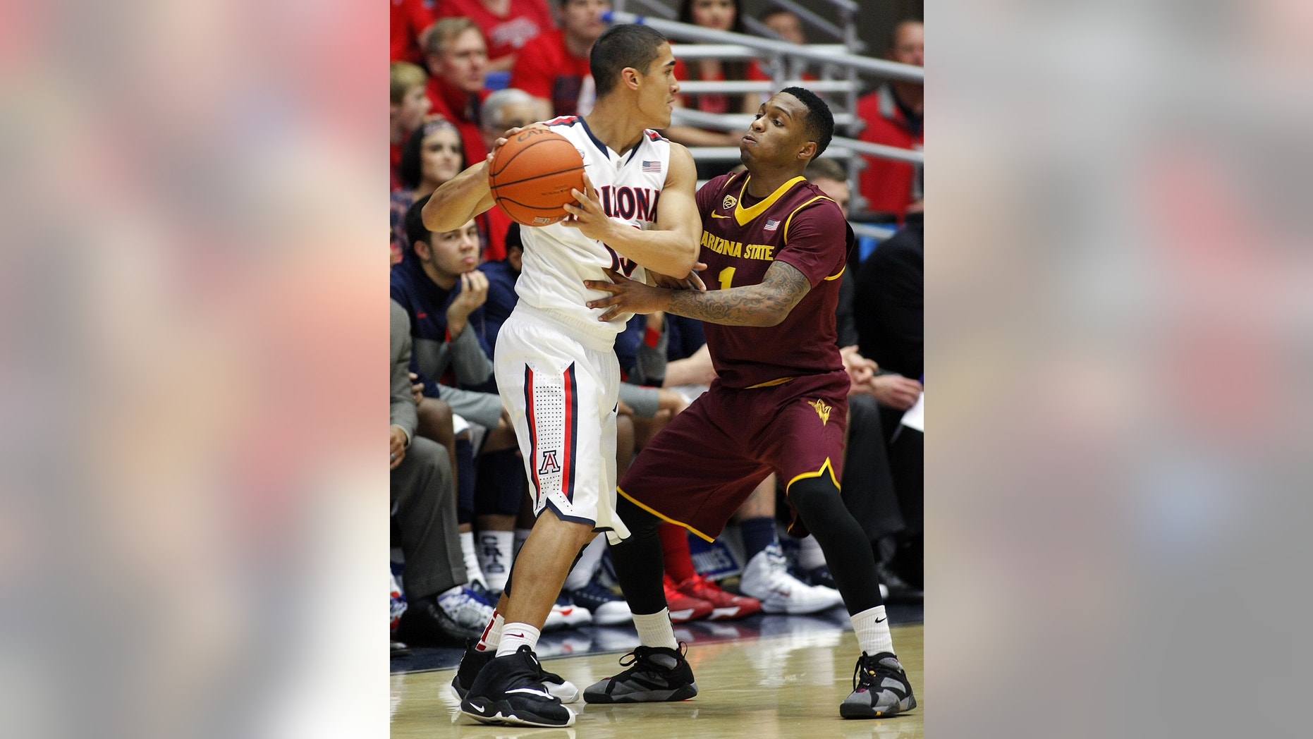 Arizona's Nick Johnson, left, looks to pass against Arizona's State's Jahil Carson during the second half of an NCAA college basketball game Thursday, Jan. 16, 2014, in Tucson, Ariz. Arizona won 91-68. (AP Photo/John MIller)