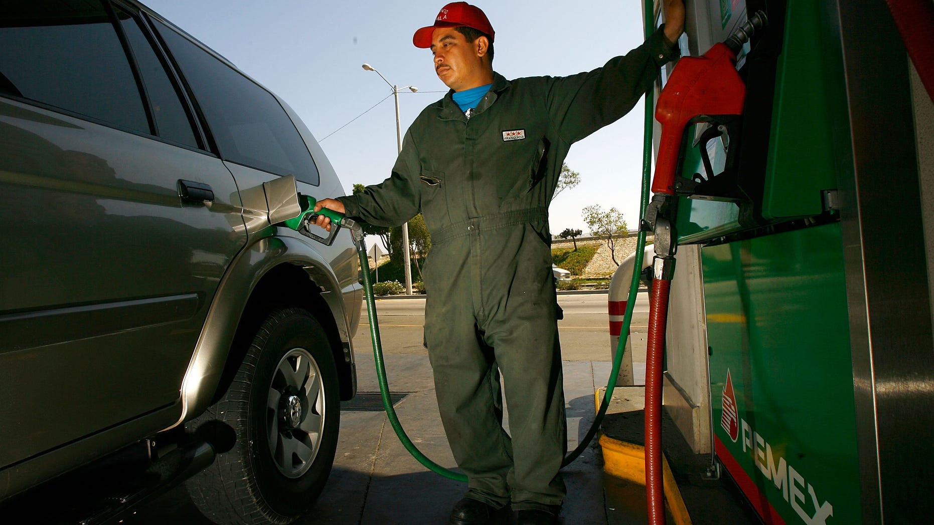 TIJUANA, MEXICO - JUNE 27: A Pemex gas station attendant fills a car registered with a California license plate on June 27, 2008 in Tijuana, Mexico. With the cost of gasoline in California around $4.60 per gallon, many drivers are buying their fuel in Mexico for about $3.20. There is a price to pay for cheaper gas though. Mexican gas is formulated with more sulfur than California gas and that can damage the emission control equipment on US cars, causing them to fail emissions tests and leading to expensive repairs. In addition, unless a driver has other business in Mexico, part of their fuel savings will be burned up idling in a line that can easily last for hours to get back into the US. (Photo by David McNew/Getty Images)