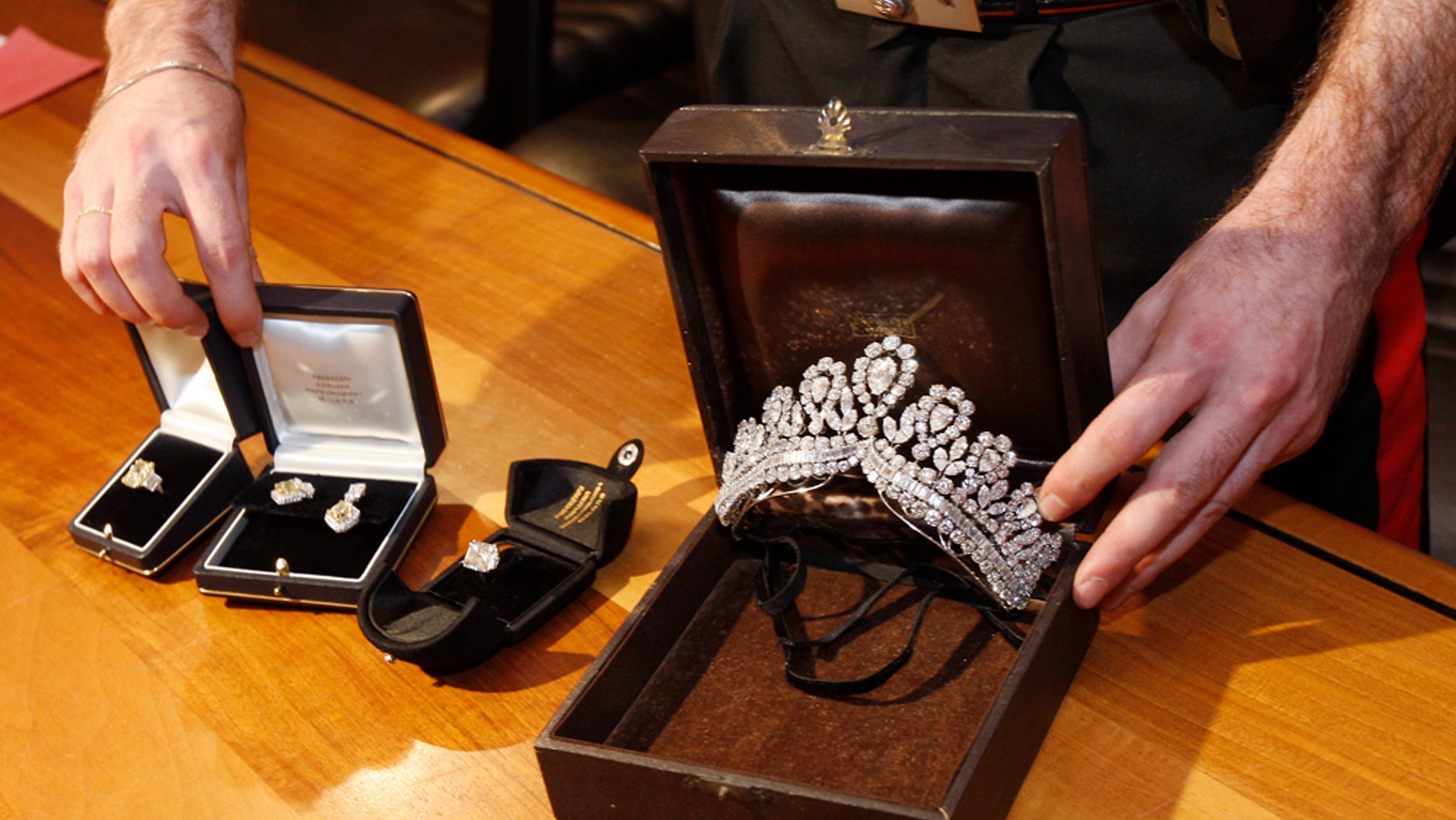 File - In this June 22, 2011 file photo, an Italian Carabinieri police officer shows recovered jewelry said to have belonged to the late Argentine first lady Eva Peron that was stolen from a store in Spain nearly two years ago. Spanish police say they have recovered euro6 million ($9 million) in jewels stolen in an elaborate scam in which one culprit posed as an Arab sheikh and another hid inside a desk across which millions in cash were changing hands. The jewels stolen from a store in Valencia were found last week in a hotel strong box in Milan, Italy and Italian officials announced this at the time. Spain's National Police gave details of the 2009 robbery and con job in a statement issued Wednesday June 29, 2011. (AP Photo/Antonio Calanni, File)