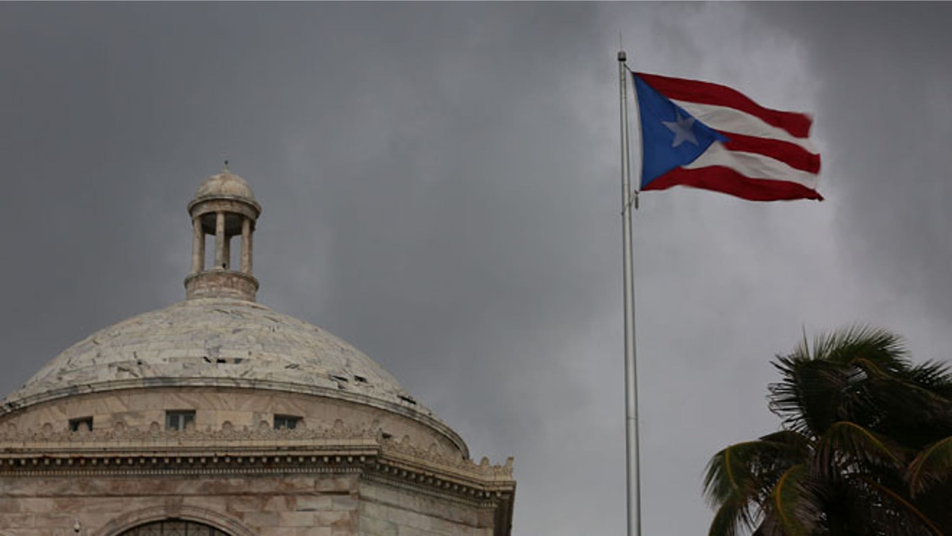 SAN JUAN, PUERTO RICO - JULY 01: The Puerto Rican flag flies near the Capitol building as the island's residents deal with the government's $72 billion debt on July 1, 2015 in San Juan, Puerto Rico. Governor of Puerto Rico Alejandro Garc?a Padilla said in a speech recently that the people of Puerto Rico will have to make sacrifices and share the responsibilities to help pull the island out of debt. (Photo by Joe Raedle/Getty Images)