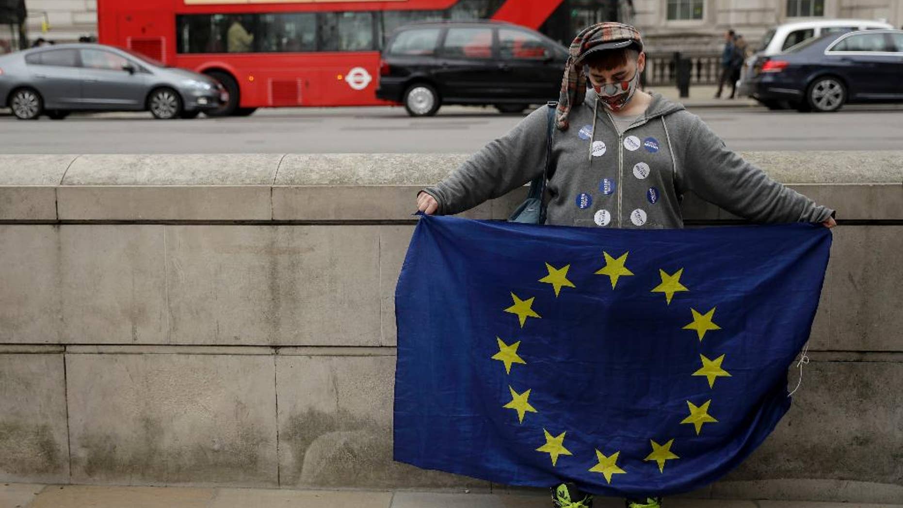 A pro-European Union membership supporter holds a European flag opposite Downing Street in central London, Wednesday, March 29, 2017. Britain will begin divorce proceedings from the European Union later on March 29, starting the clock on two years of intense political and economic negotiations that will fundamentally change both the nation and its European neighbours. (AP Photo/Matt Dunham)