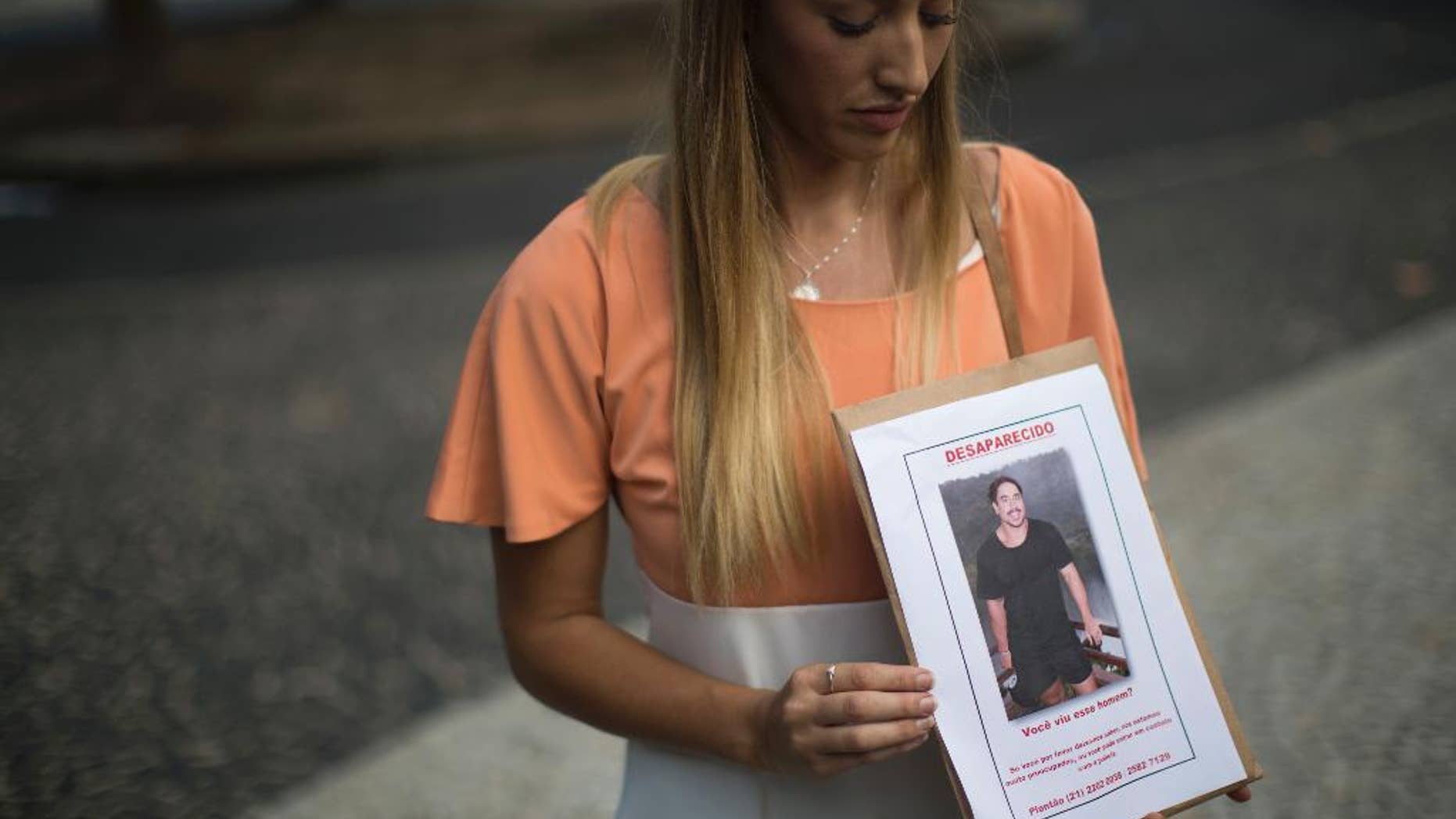 FILE - In this June 3, 2016 file photo, Bonnie Cuthbert, of Australia, shows a photo of her missing boyfriend Rye Hunt, 25, during a press conference in Rio de Janeiro, Brazil. Hunt, an electrician who worked at a mine in western Australian, was in Rio as part of a world trip with a friend where he was last seen on May 21. On Saturday, June 11, police confirmed that the body that washed up on a beach near Rio de Janeiro three days prior is Hunt, adding that investigators have not been able to establish the cause of death. (AP Photo/Felipe Dana, File)