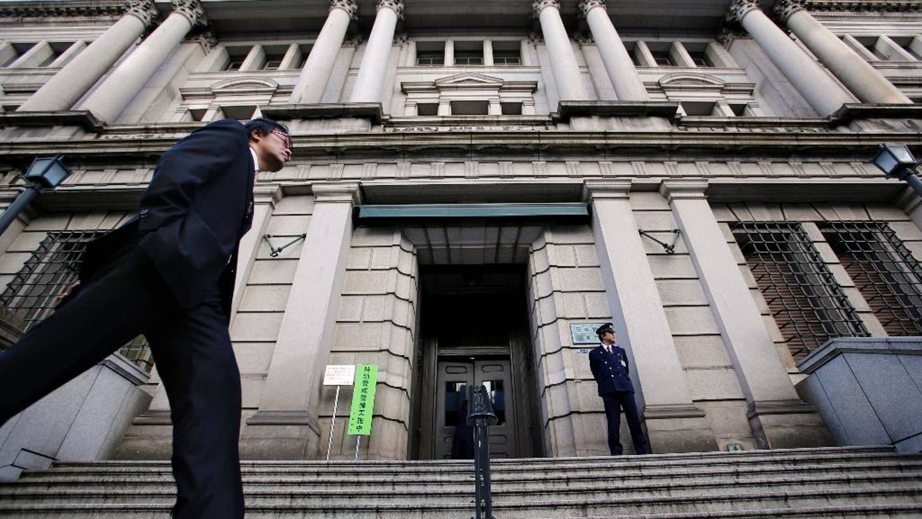 FILE - In this Nov. 19, 2014 file photo, a man walks by the Bank of Japan headquarters in Tokyo. Japan's central bank says sentiment among big manufacturers slipped in the most recent quarter, underlying the shaky footing for the nation's economic growth. The closely watched survey, released Thursday, Oct. 2015, fell 3 points to a plus 12 in September. (AP Photo/Shizuo Kambayashi, File)