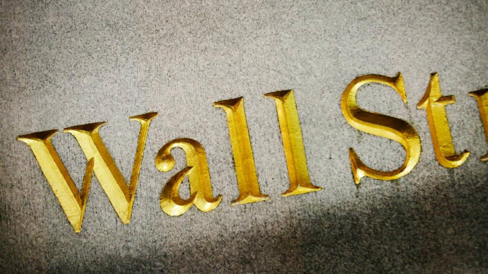 FILE - This Oct. 8, 2014, file photo, shows a Wall Street address carved in the side of a building, in New York. Global stocks struggled on Monday, Feb. 2, 2015, after Chinese manufacturing weakened, though European markets were stable after France endorsed Greek efforts to ease its bailout terms. (AP Photo/Mark Lennihan, File)