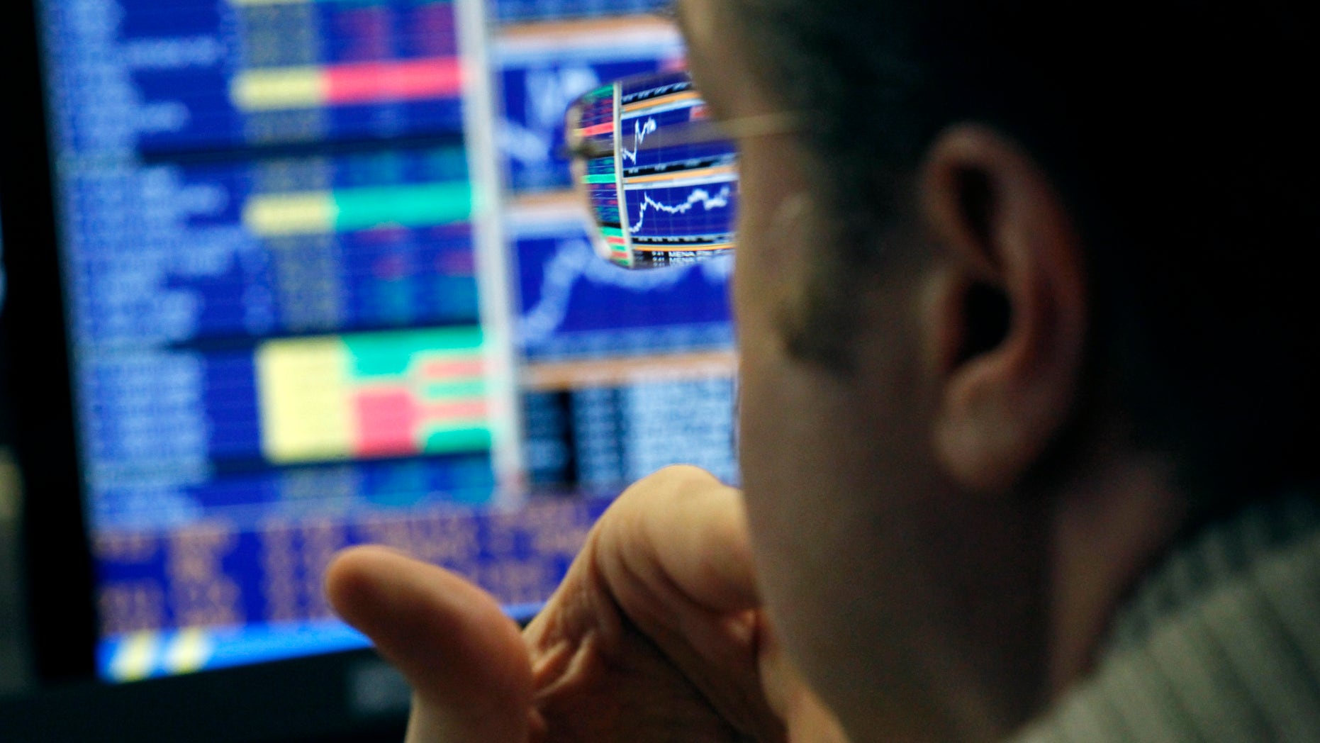 Graphs are reflected in the spectacles of a broker while working in a trading room of a Portuguese bank in Lisbon, Wednesday, Feb. 20, 2013. Portugal has raised euro 1.5 billion ($2 billion) in a debt sale, with the interest rate it is paying on a 12-month Treasury bill showing a significant drop as market confidence in the bailed-out country continues to improve. (AP Photo/Francisco Seco)