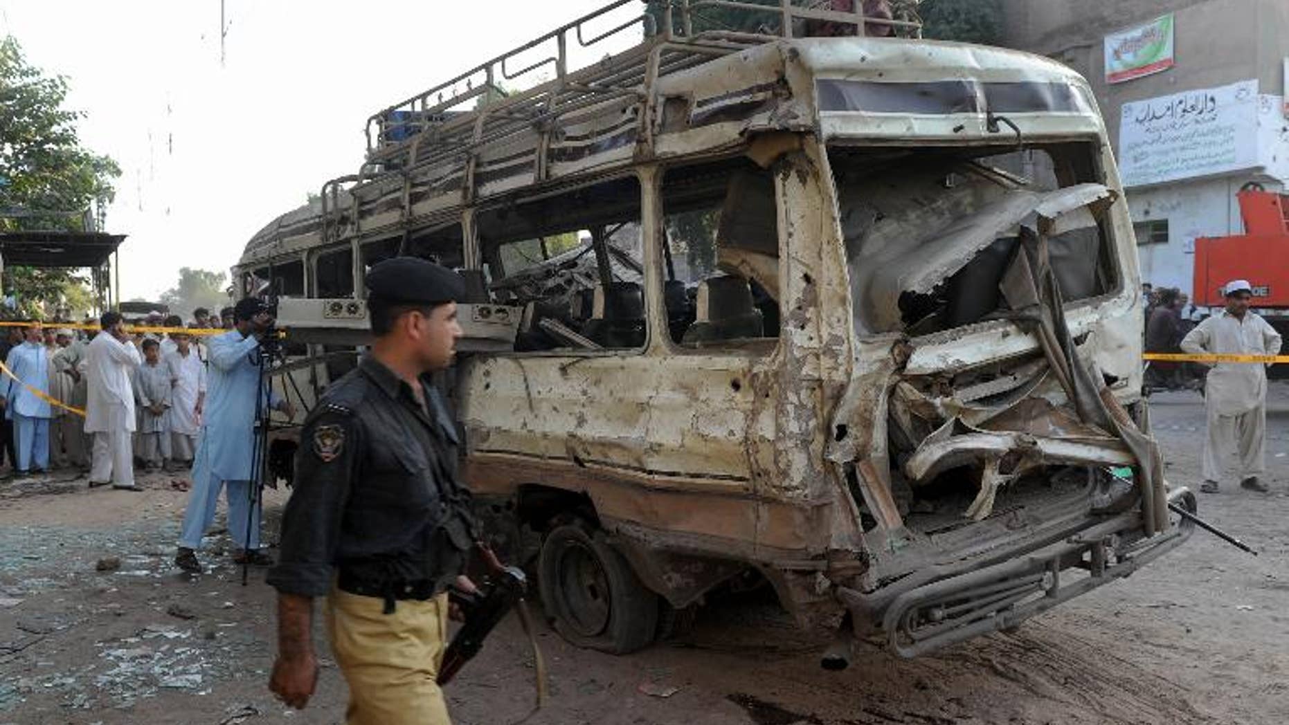 A Pakistani policeman walks past the wreckage of a passenger bus following an explosion in Peshawar, on September 19, 2012