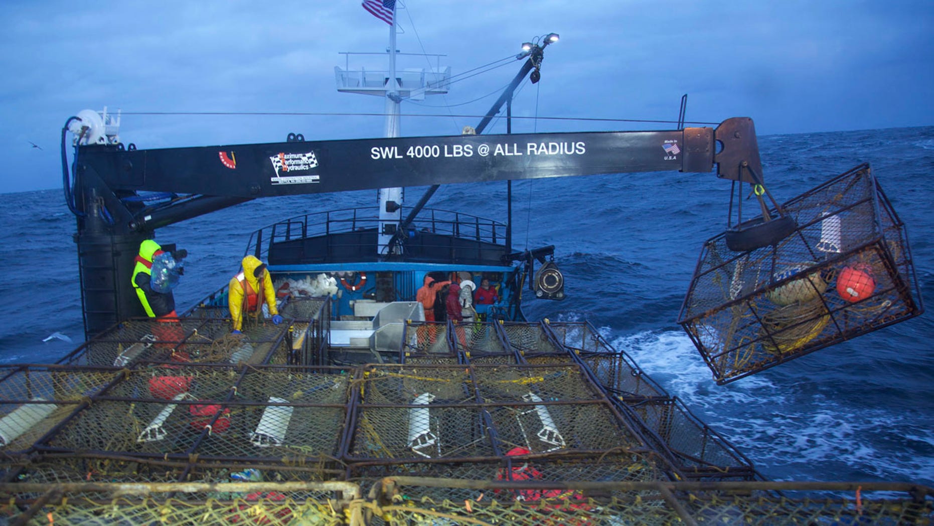 This image released by Discovery Channel shows a crane removing a pot from the stack as the Summer Bay crew sets its gear in "Deadliest Catch."