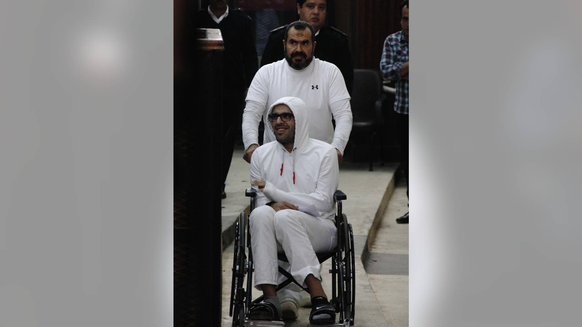 In this March 9, 2015 photo, Mohammed Soltan is pushed by his father Salah during a court appearance in Cairo, Egypt. Egyptian officials say authorities have freed Soltan, a dual U.S.-Egyptian citizen, Saturday May 30, 2015, Soltan had been sentenced to life in prison on charges of financing an anti-government sit-in and spreading "false news." (AP Photo/Heba Elkholy) ***EGYPT OUT***