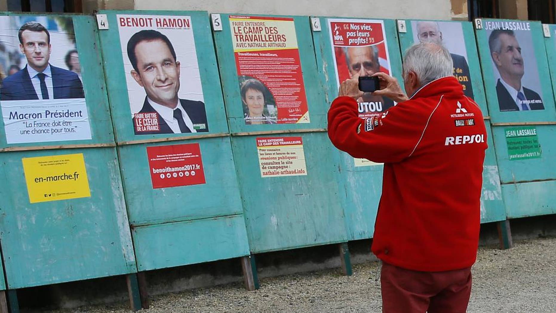 A man takes a picture of electoral posters displaying posters of the presidential candidates in Espelette, southwestern France, Friday, April 14, 2017. The two-round presidential election is set for April 23 and May 7. (AP Photo/Bob Edme)