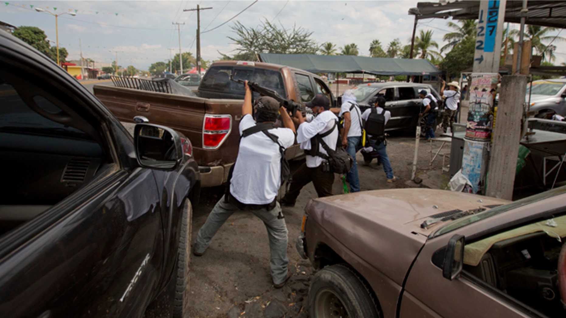 FILE - In this Jan. 12, 2014 file photo, the Self-Defense Council of Michoacan (CAM) engage in a firefight as they try to flush out alleged members of the Knights Templar drug cartel from Nueva Italia, Mexico. The vigilantes say they are liberating territory in the "Tierra Caliente" and are aiming for the farming hub of Apatzingan, said to be the cartel's central command. Mexican military troops stayed outside the town and there were no federal police in sight. (AP Photo/Eduardo Verdugo, File)