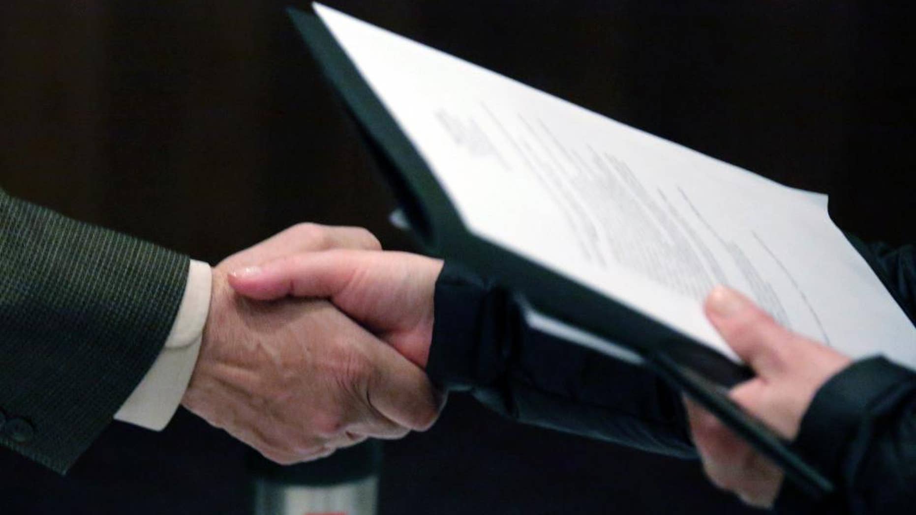 In this April 22, 2015 photo, Ralph Logan, general manager of Microtrain, left, shakes hands with a job seeker during a National Career Fairs job fair in Chicago. The U.S. Labor Department reports on the number of people who applied for unemployment benefits last week on Thursday, May 28, 2015. (AP Photo/M. Spencer Green)