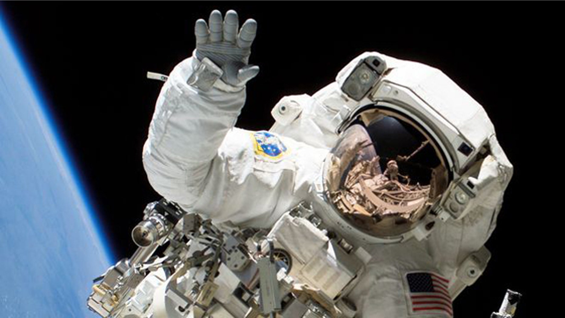 Astronaut Heidemarie M. Stefanyshyn-Piper waves at the camera during a spacewalk.